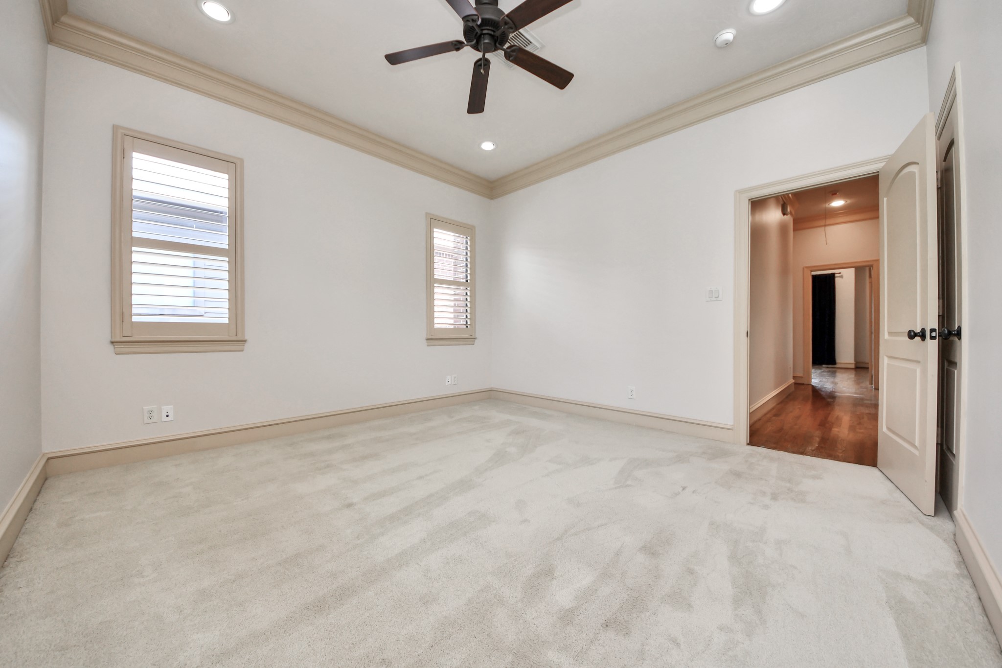 Spacious and bright room with plush carpeting, recessed lighting, and a ceiling fan, offering comfort and style.