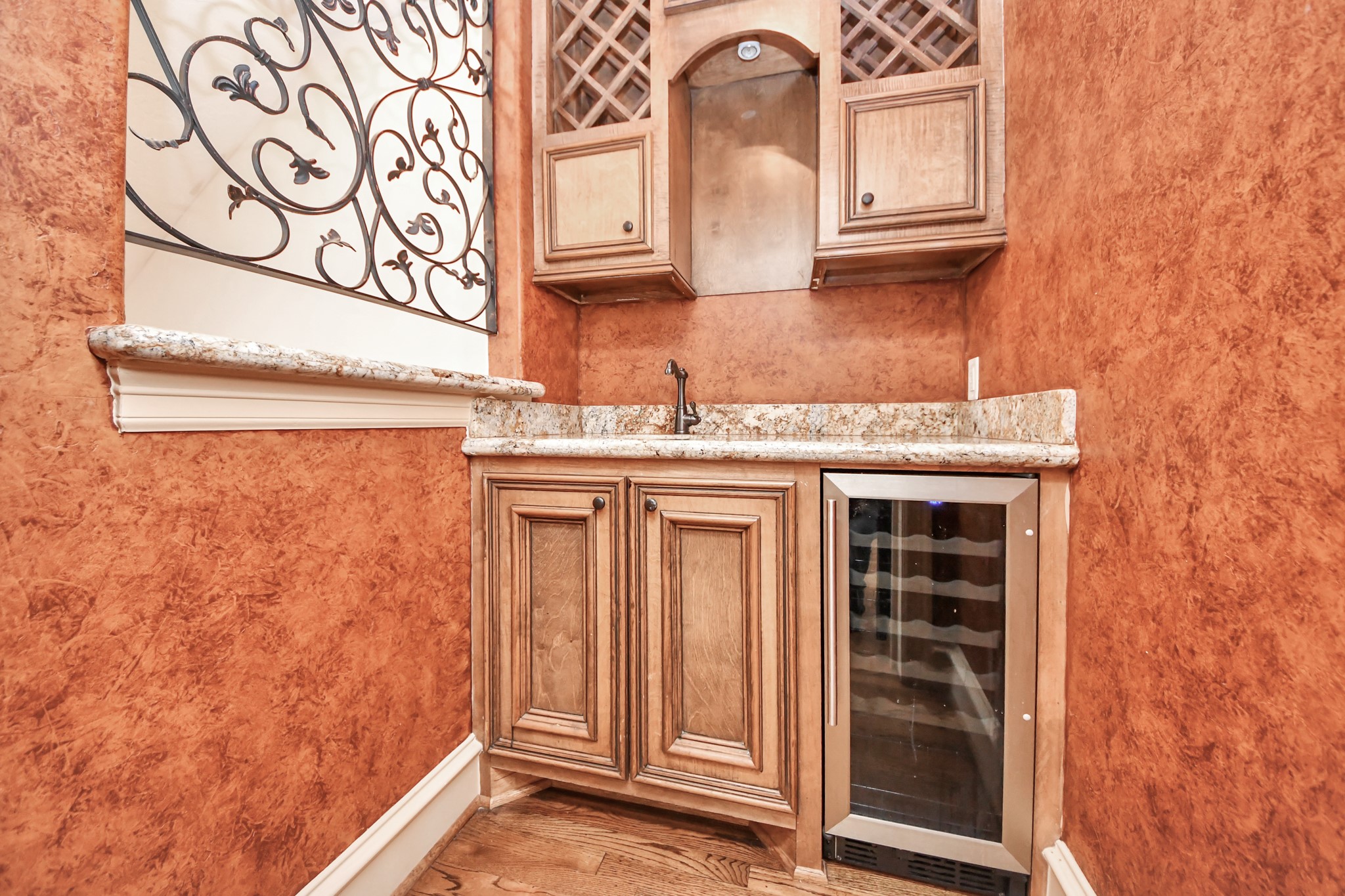 Charming wine grotto with elegant cabinetry, granite countertops, a wine rack, and a built-in wine cooler, perfect for entertaining.