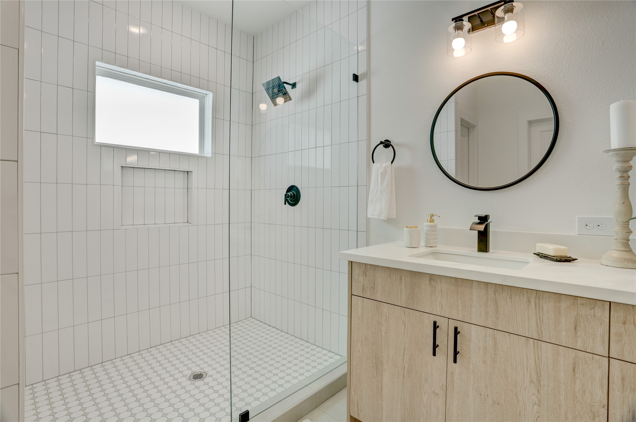 The primary bath has a frameless standing shower with subway tile surround.