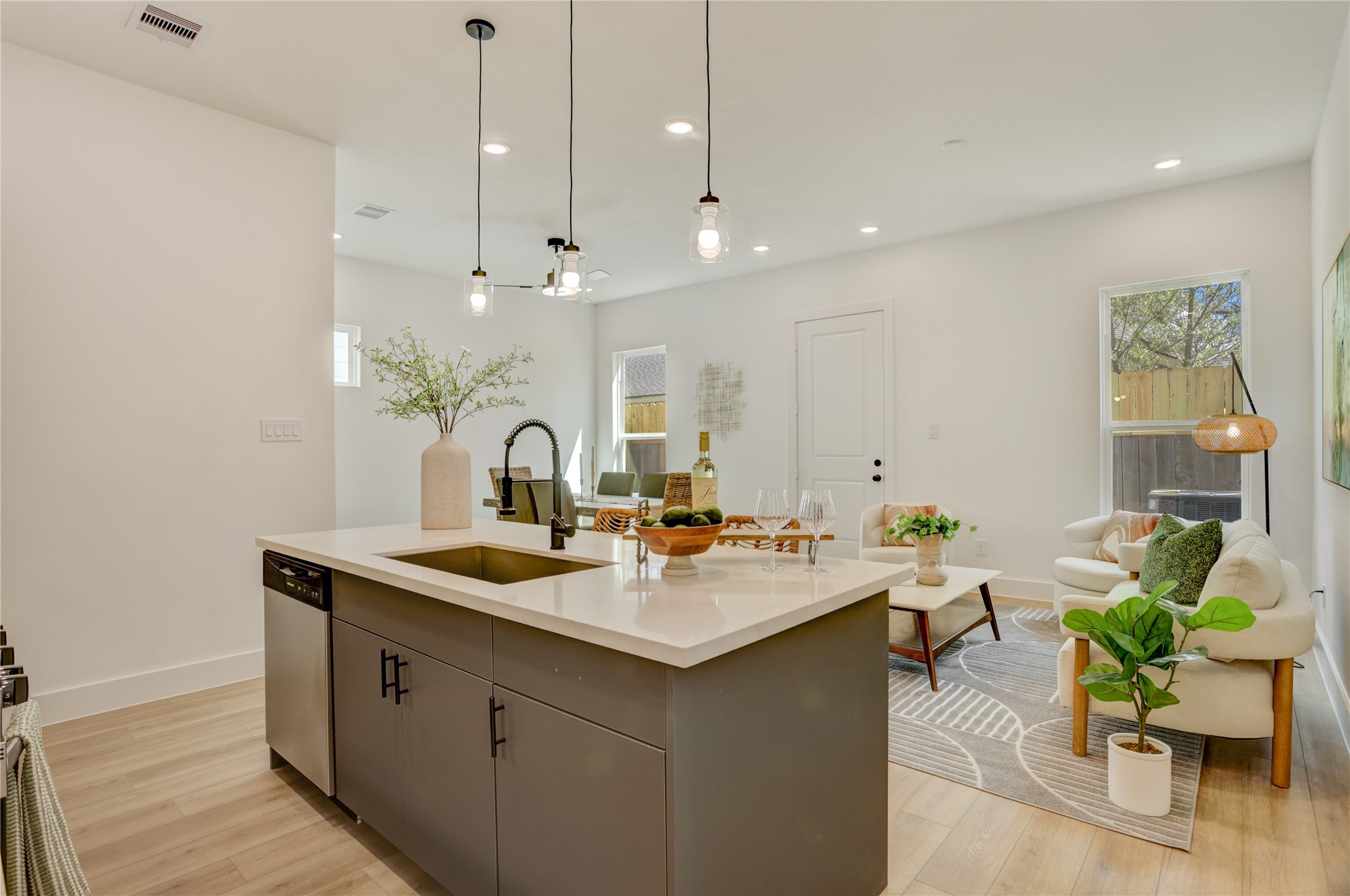 The kitchen island has a stainless steel undermount Kohler sink with retractable faucet and drip accessories, and custom pendant lights.