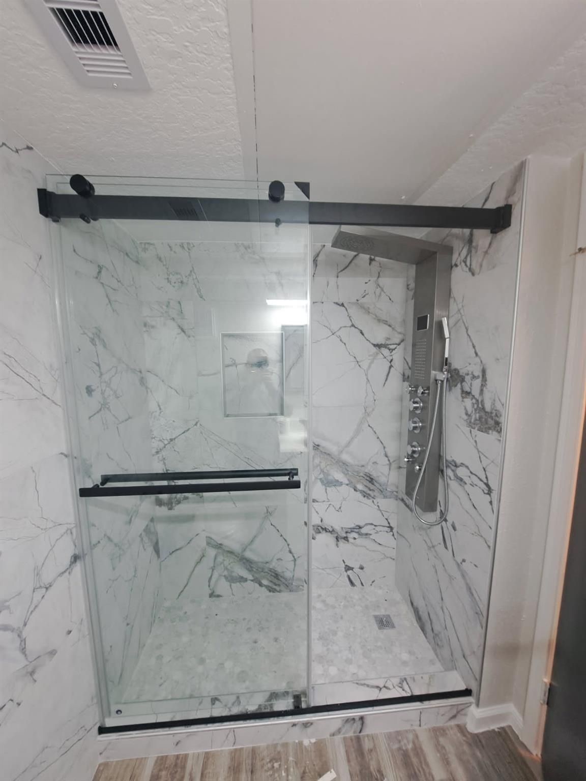 Spa like shower with multiple rain shower heads and floor to ceiling marble tile
