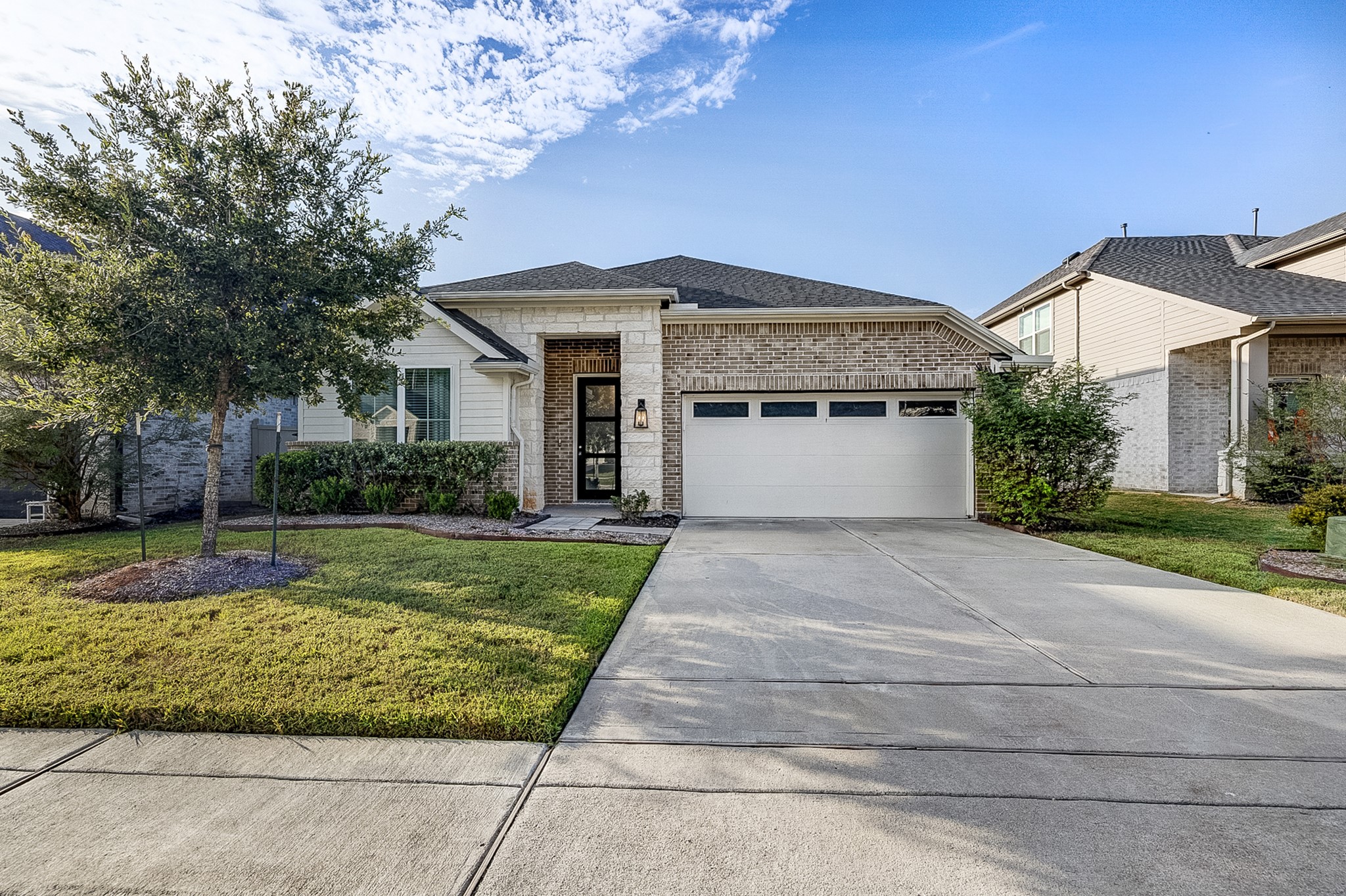 Charming single-story home with a brick facade and a welcoming front porch. The well-maintained lawn and trees enhance curb appeal, while the spacious driveway leads to a two-car garage.