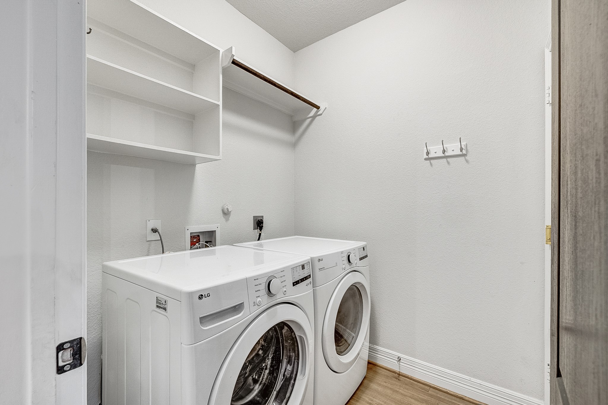 Convenient laundry room with modern washer and dryer, ample shelving, and hanging space for easy organization.