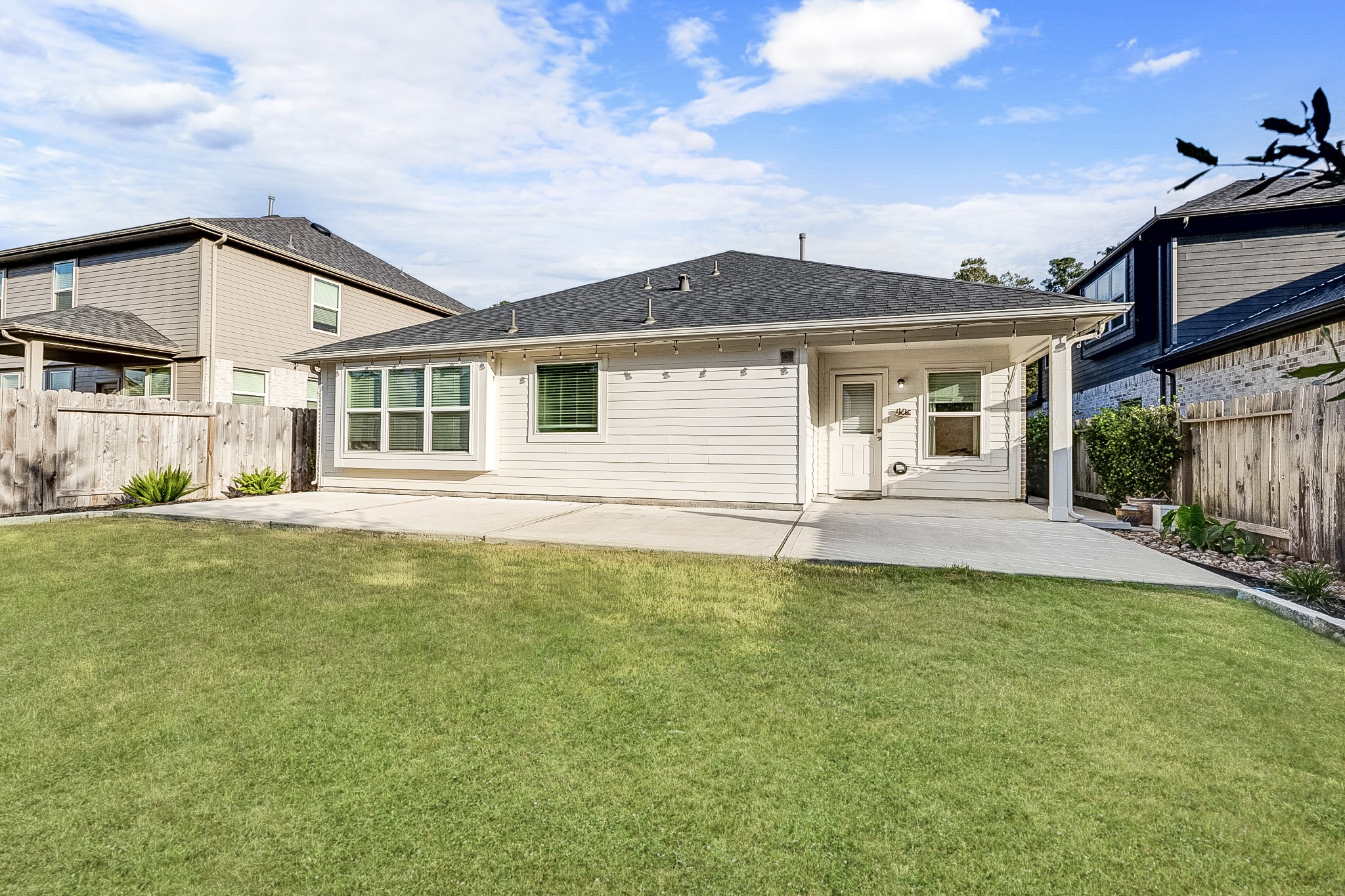 Charming single-story home features a spacious backyard with a well-maintained lawn and a covered patio area, perfect for outdoor gatherings.