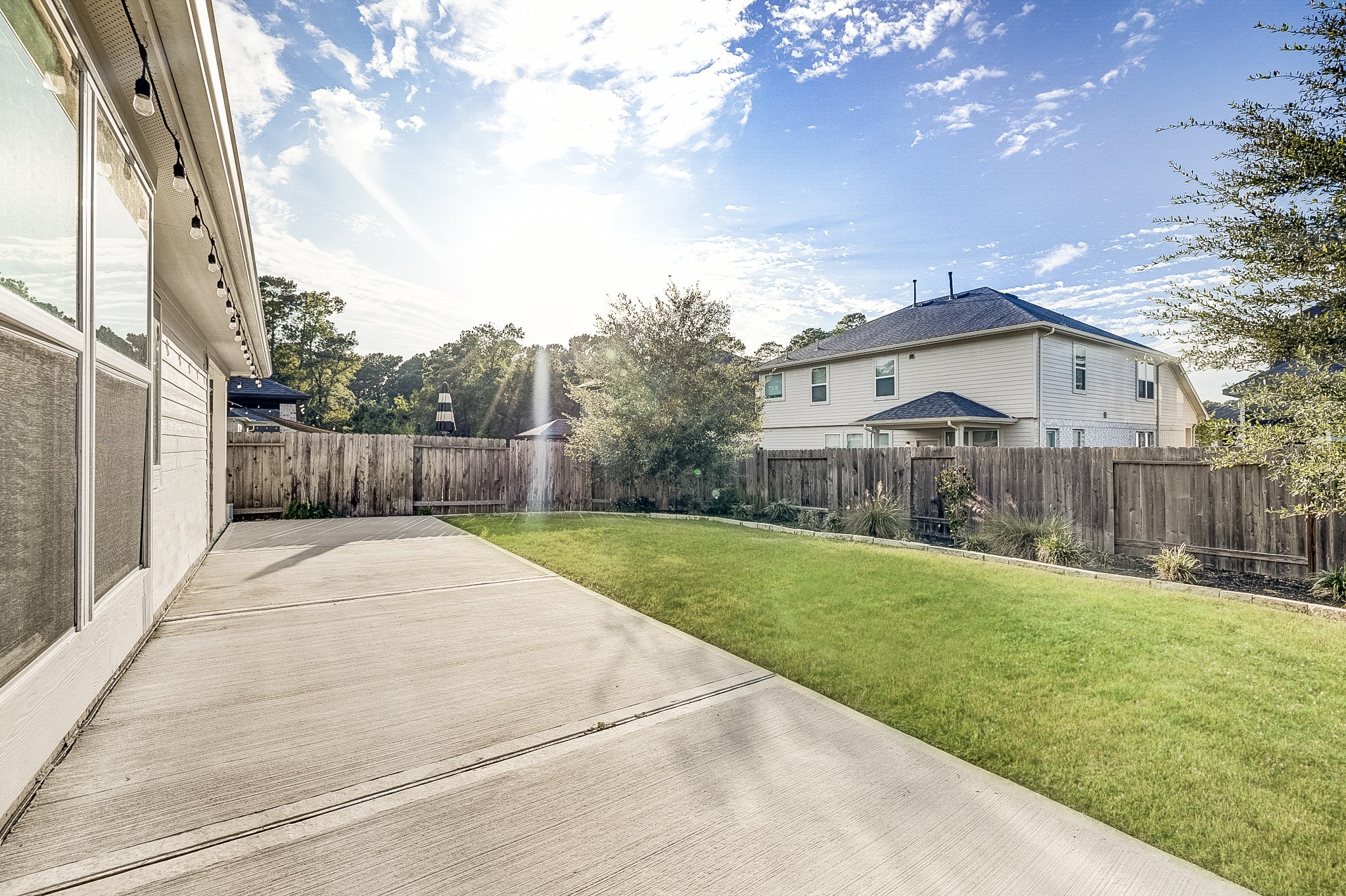 Expansive backyard with a spacious concrete patio, perfect for outdoor entertaining, complemented by a well-maintained lawn and surrounded by a privacy fence.