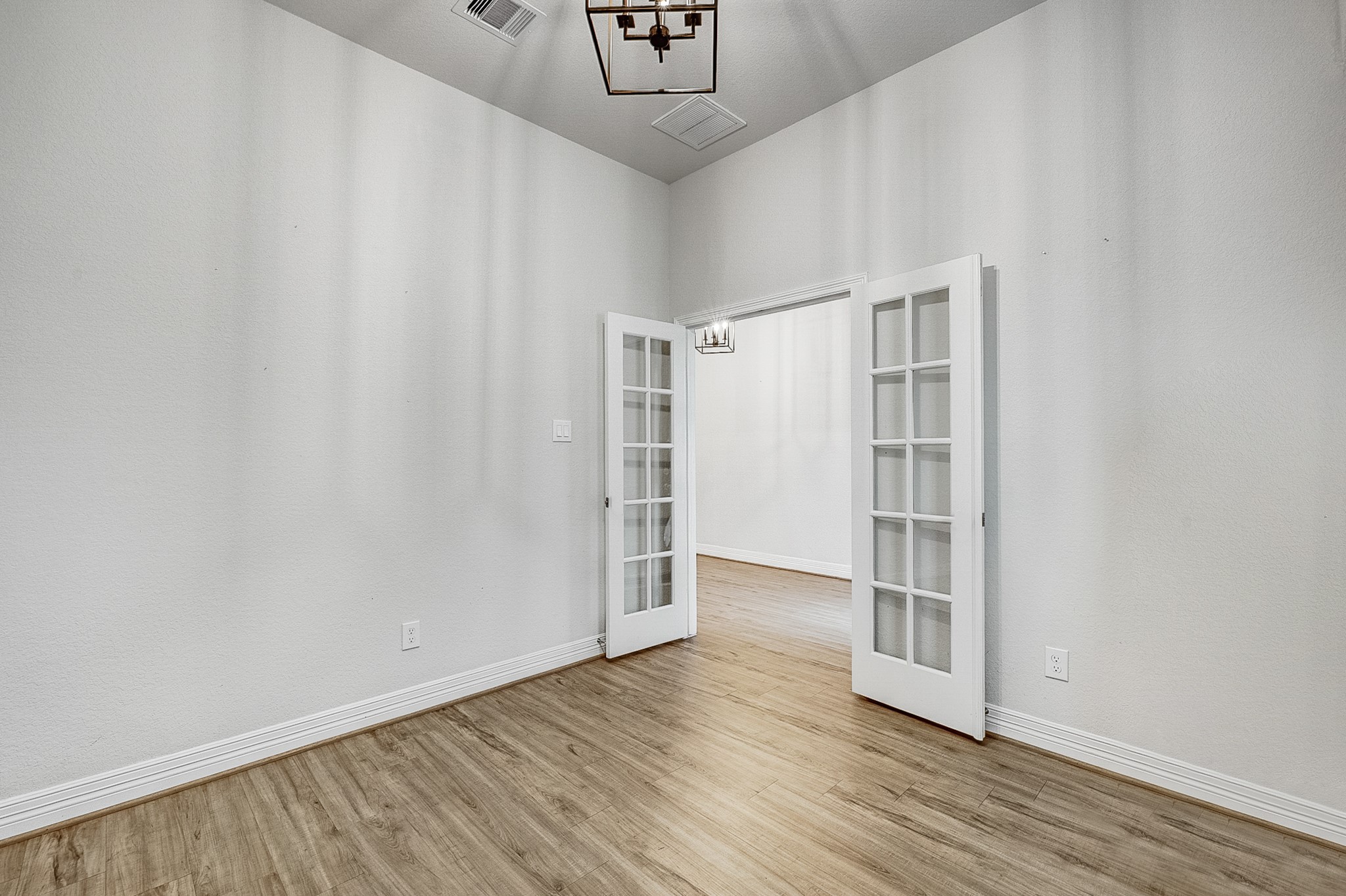 Elegant room featuring French doors and wood flooring, perfect for a home office or cozy retreat.