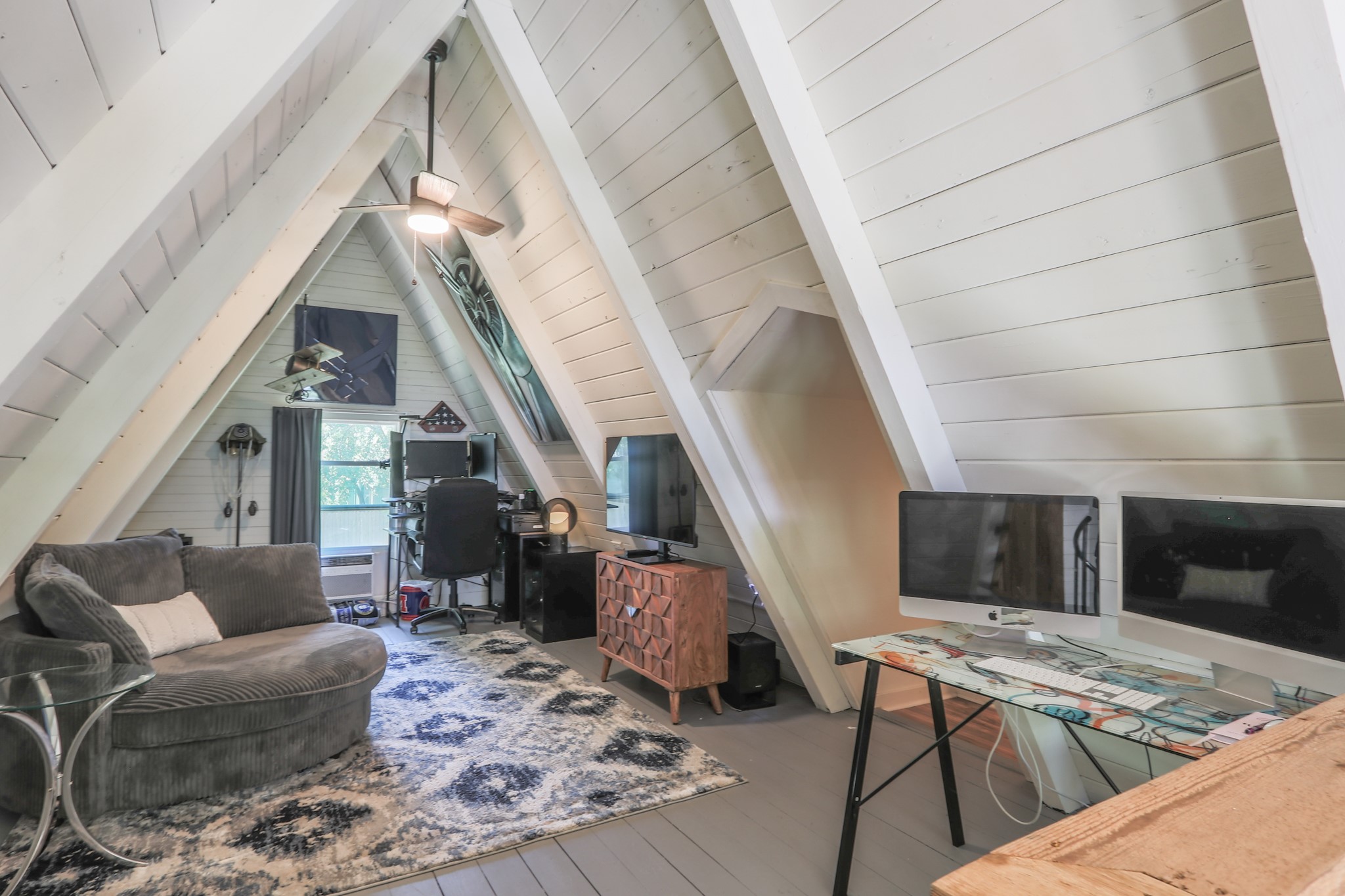 The upper loft with ship lap ceilings, ceiling fan, window unit to keep it comfortable.