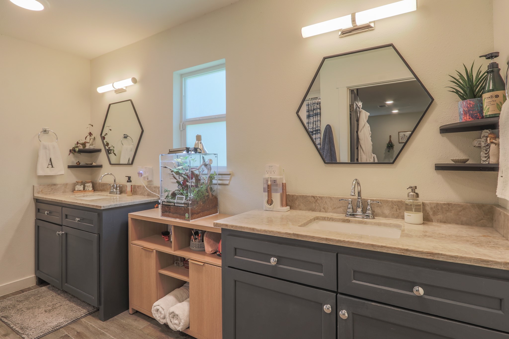 The primary ensuite bath feature modern lighting, mirrors and cabinetry.