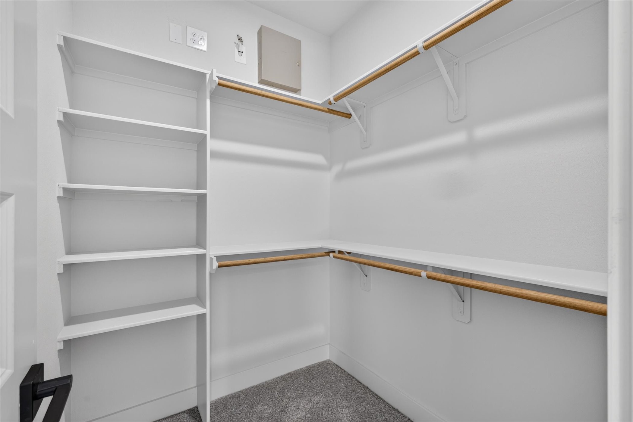 This photo shows a spacious walk-in closet with double hanging rods and built-in shelving, providing ample storage space. The neutral gray walls and white trim create a modern, clean look.