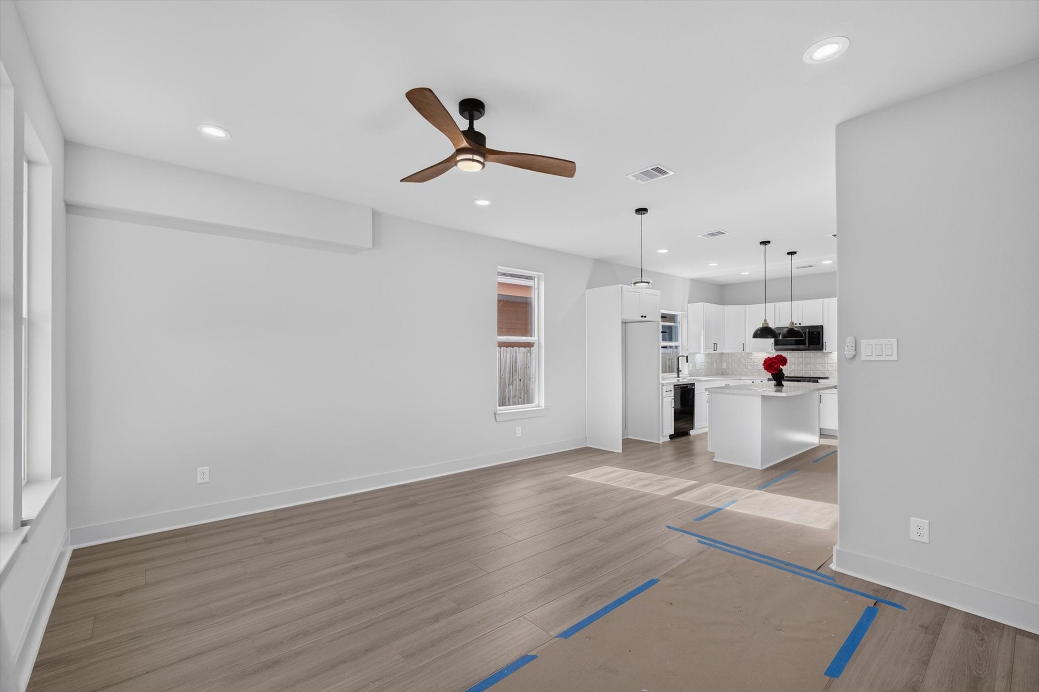Modern kitchen with white cabinetry, stainless steel appliances, and a sleek gas range. The countertops are a clean, light color, complemented by a white subway tile backsplash. The room has a bright and airy feel, accented by dark hardware and a neutral wall color.