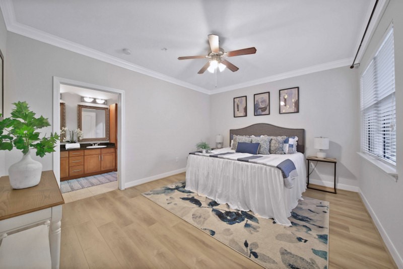 The view of large primary suite W/New wood floor, crown molding and ceiling fan.
