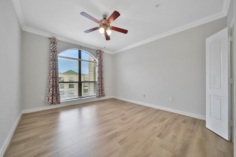 The view of secondary bedroom W/New wood flooring, crown molding and ceiling fan.