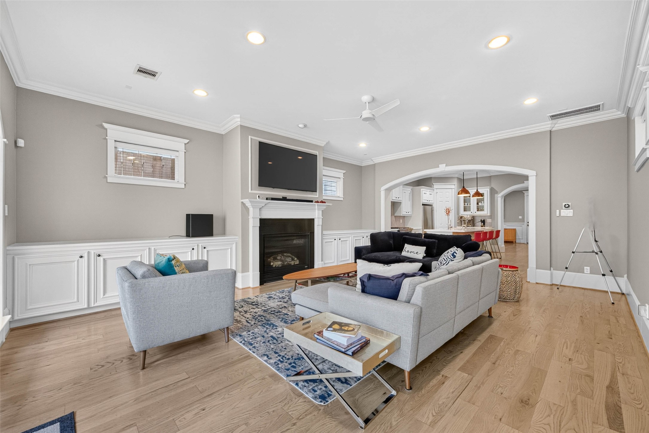 Custom millwork and a handsome fireplace anchor this spacious living room, while graceful arches connect the heart of the home, the kitchen!