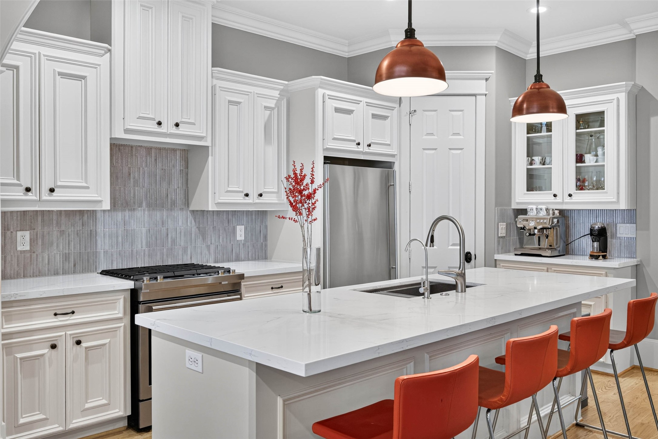 Exceptional cabinetry surrounds the kitchen, complemented by stainless appliances, dramatic copper pendants and a dedicated coffee bar.