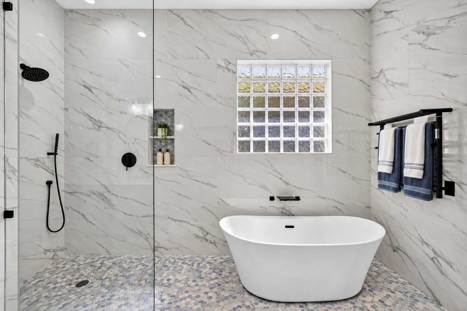 Spa-inspired wet room features a freestanding soaking tub, oversized walk-in shower, designer tile, and sleek matte-black fixtures.