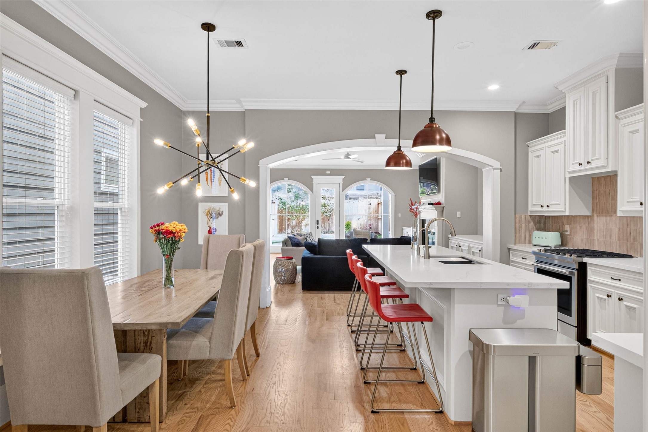 Sunlight pours across the hardwood floors, highlighting the graceful connection between dining, kitchen and living spaces.