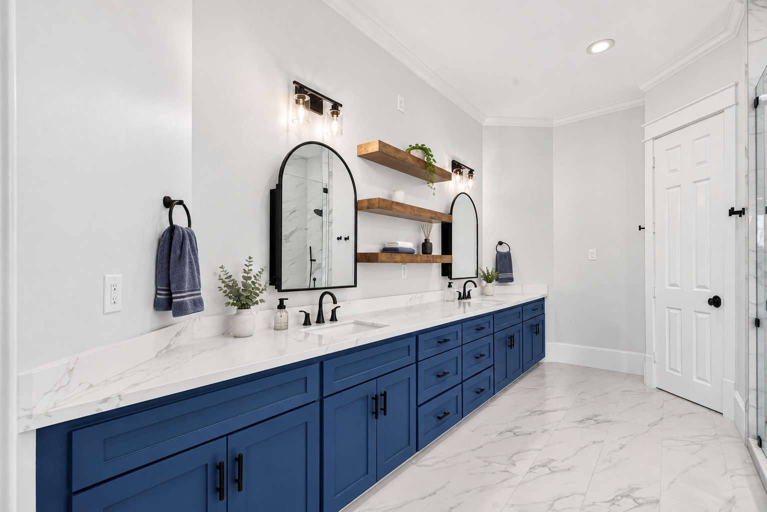 This beautifully re-envisioned primary bathroom pairs rich blue cabinetry with with an expansive quartz counter, 2 sinks, warm wood accents, abundant storage, designer lighting, and gorgeous mirrors that also open to provide off-counter storage and easy access to your daily necessities!