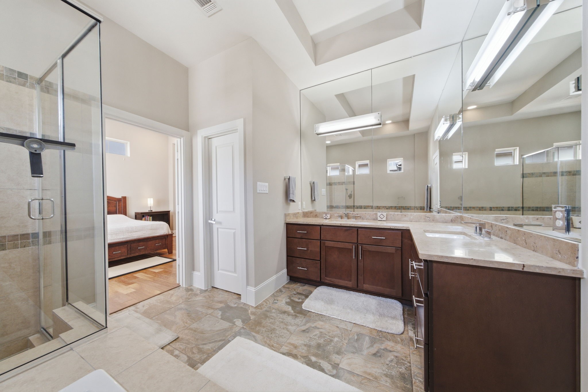 An L-shaped dual vanity provides generous countertop space, making busy mornings feel effortless while offering abundant cabinet storage below.