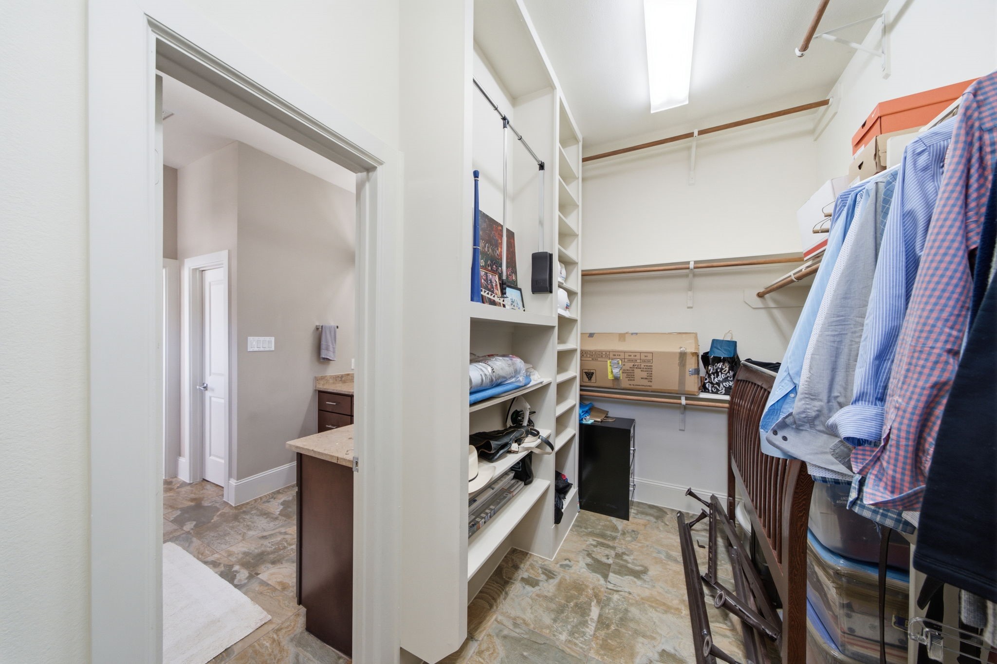 Large walk in closet with custom built in shelves and a three tier hanging system.