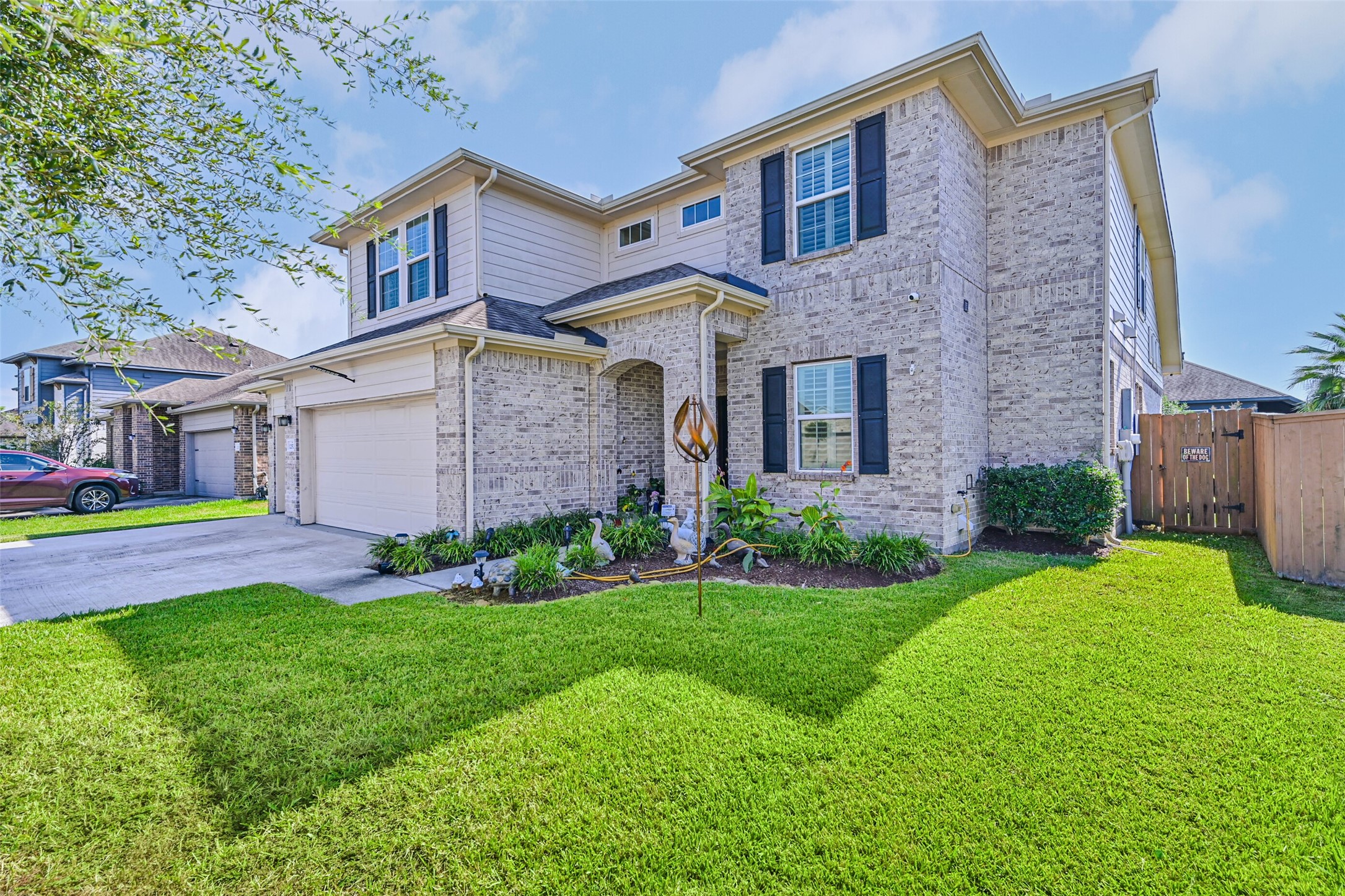 Attractive brick exterior with landscaped flower beds, mature greenery, and a welcoming covered entryway.