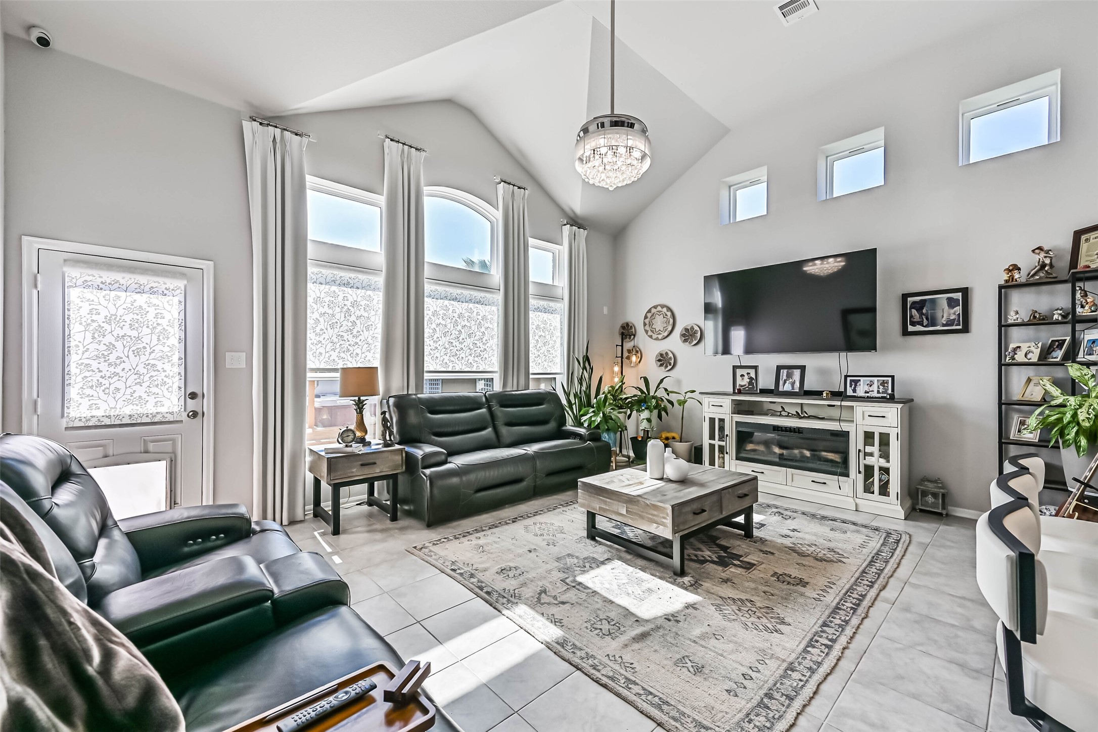 Bright and inviting living room featuring soaring ceilings, beautiful windows, decorative lighting, and an open, spacious layout.