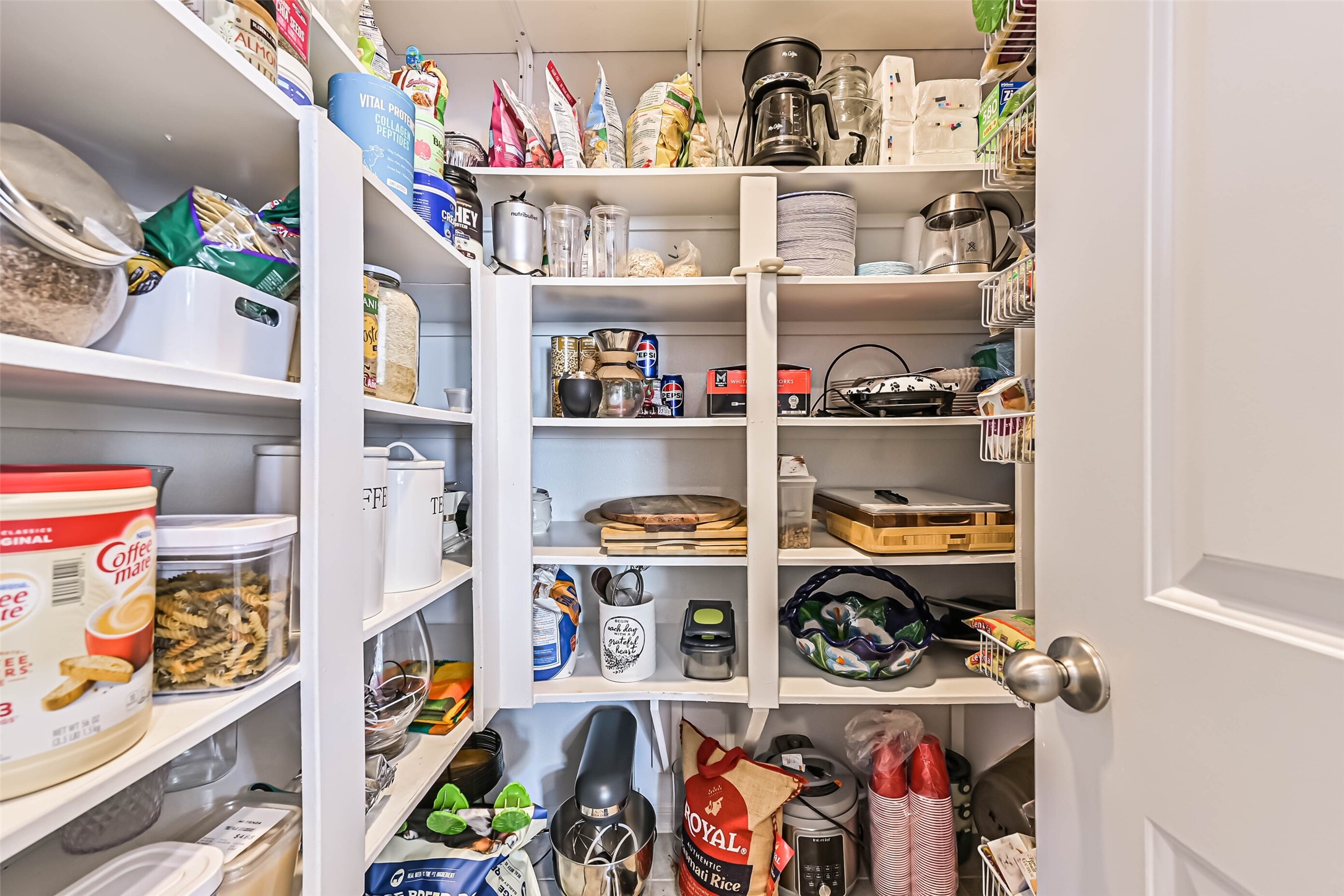 Generously sized walk-in pantry with multiple shelves, providing excellent storage for groceries, small appliances, and kitchen essentials.