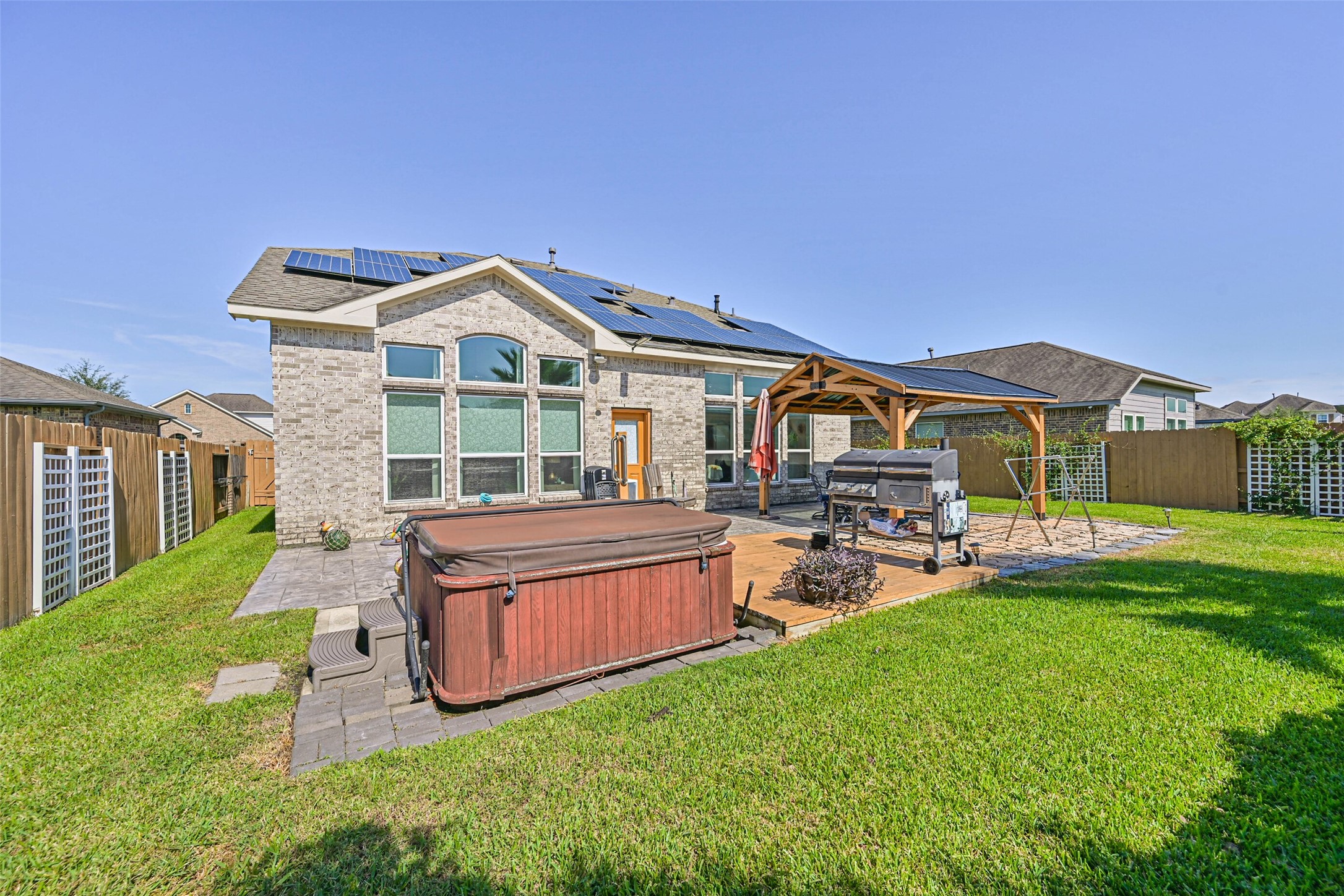 Beautiful backyard retreat featuring a private hot tub, expansive patio, covered outdoor entertaining area, and solar panels.