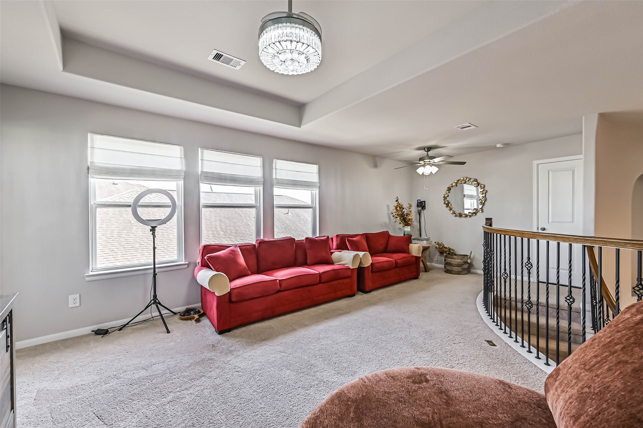 Bright and inviting second-floor living space with multiple windows, decorative ceiling details, and beautiful wrought-iron railing.