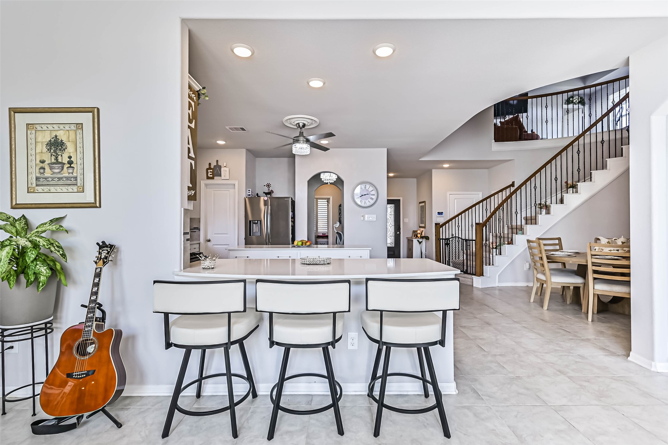 Open-concept design seamlessly connects the kitchen, dining area, and elegant curved staircase, creating an inviting atmosphere.