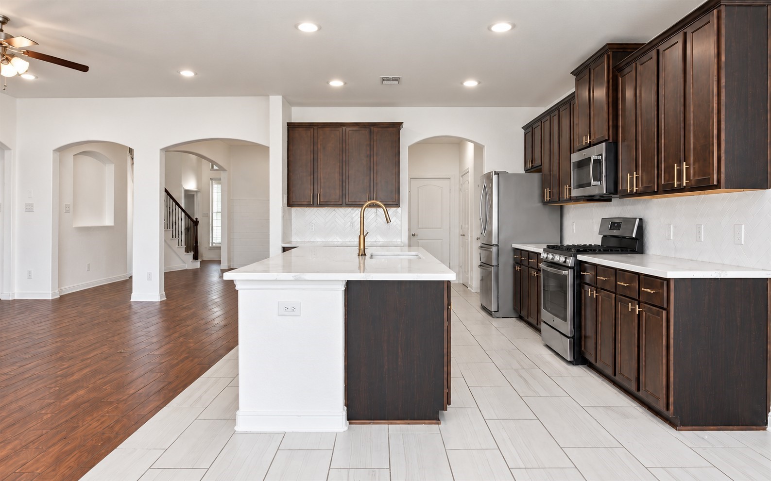 The kitchen is where this home really shines. Dark wood cabinetry, white quartz countertops, gold fixtures, stainless steel appliances and a herringbone tile backsplash making this space look stunning.