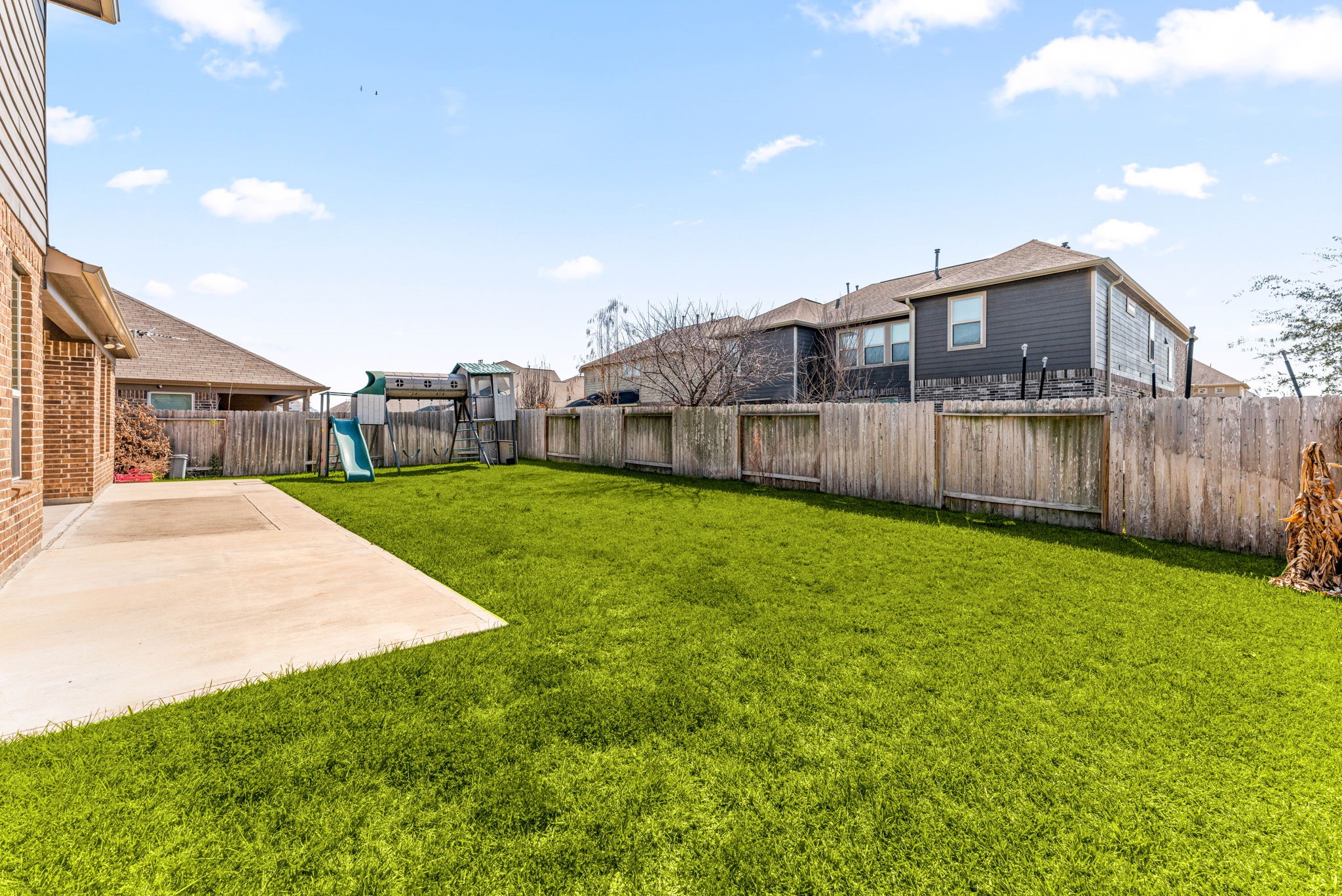 A wider view of the backyard showing just how much space there is, plenty of grass, a solid fence for privacy and room for anything from a garden to a pool down the road.