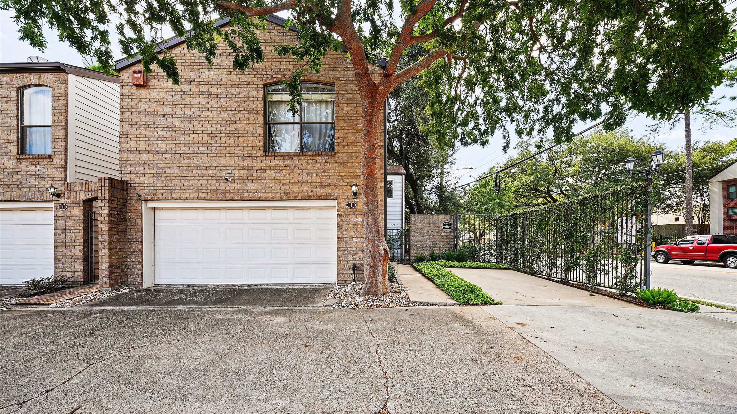 2555 Bering Drive is a charming brick townhouse with a spacious two-car garage and a beautifully landscaped additional guest parking area that most units don't offer, complemented by a mature tree providing shade and privacy.