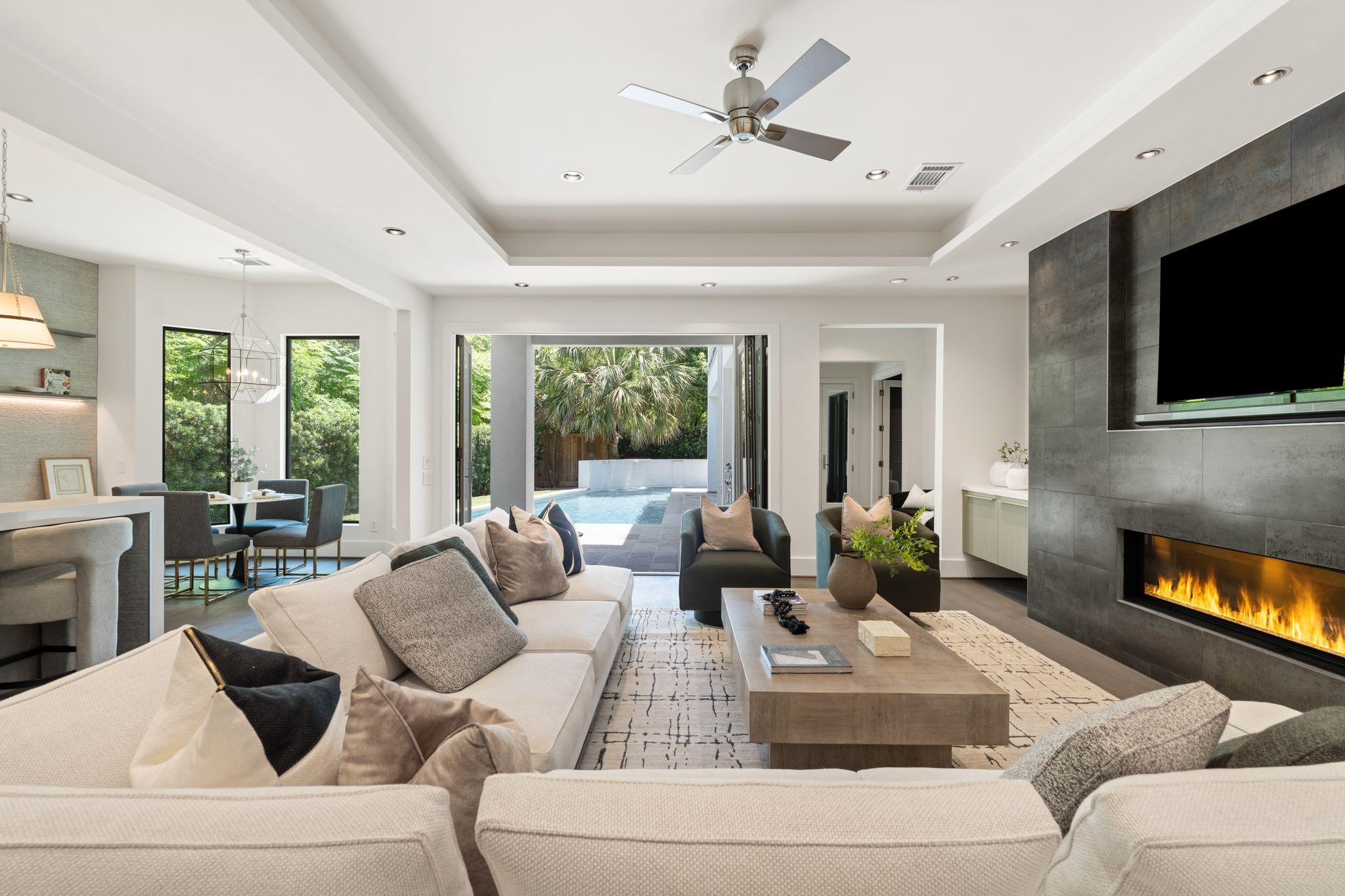 Designed for effortless entertaining, the spacious family room features a dramatic linear fireplace and walls of sliding glass that open directly to the sparkling pool and outdoor living spaces.
