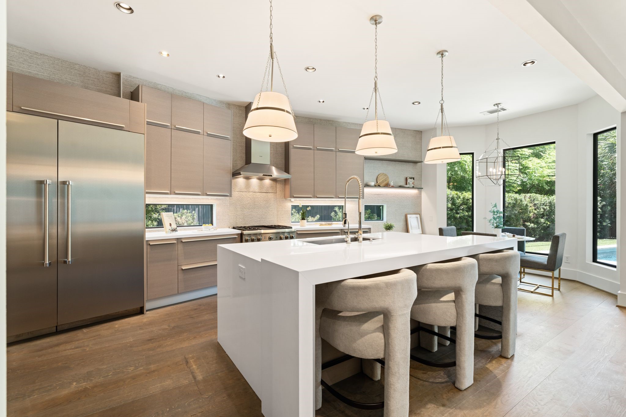 Designed for both entertaining and everyday living, the gourmet kitchen offers an expansive island, professional-grade appliances, sleek custom cabinetry, and sunlit breakfast area overlooking the pool.