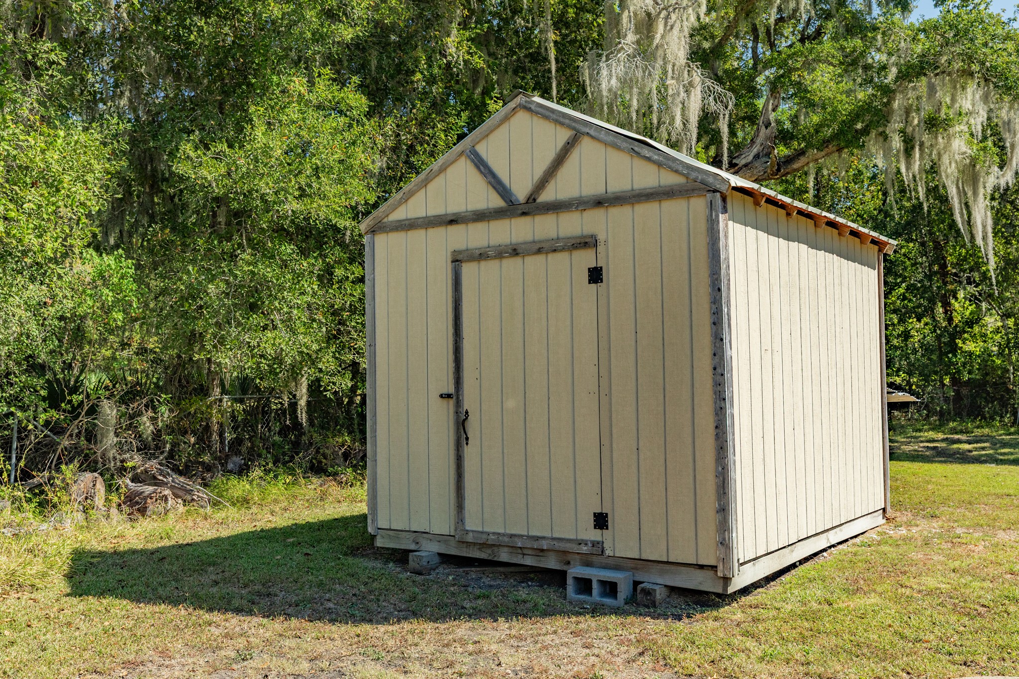 Convenient freestanding storage shed features neutral siding, wood trim, and a single entry door. A practical addition for storing lawn equipment, tools, and outdoor essentials.