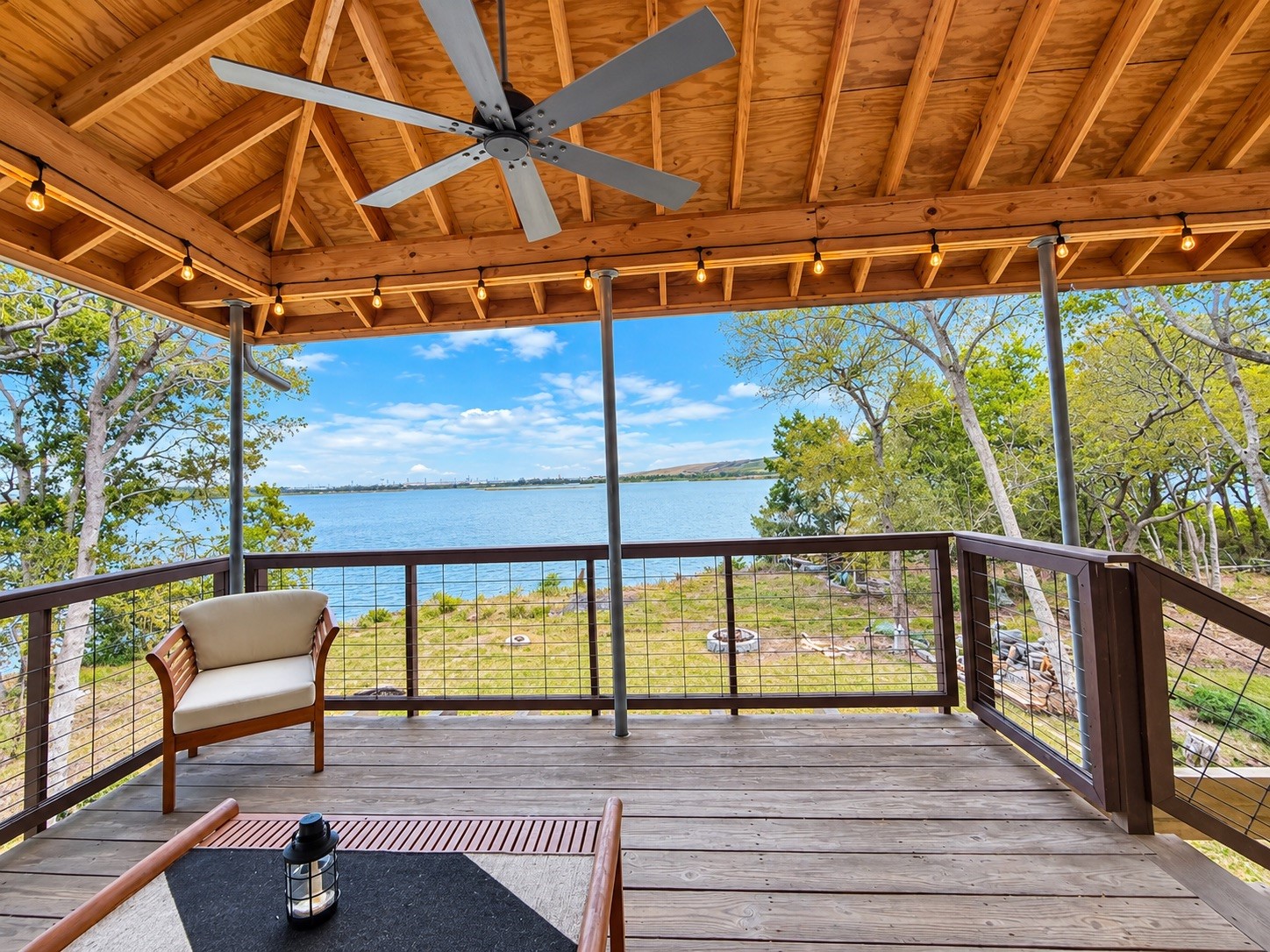 Spacious covered deck with stunning lake views, rustic wood ceiling, and cozy seatingperfect for outdoor relaxation.