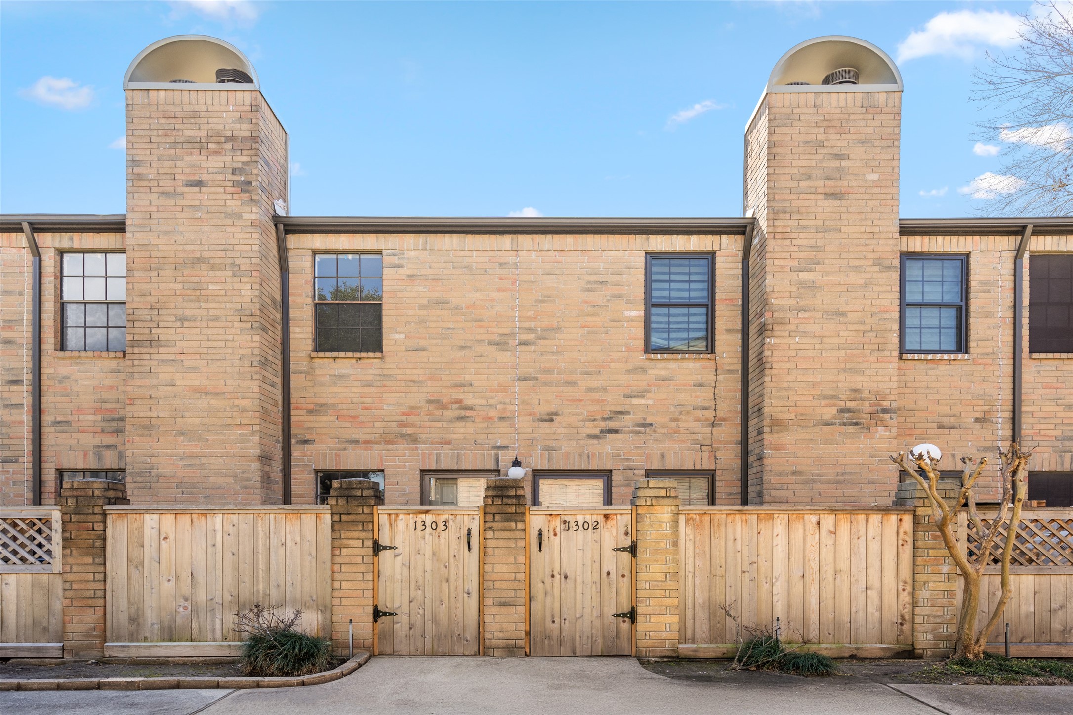 Welcome to 9850 Pagewood Lane #1302, a charming townhome with a timeless brick faade and a private gated entry. The warm brick exterior, accented by classic black-trim windows and dual chimneys, exudes character and curb appeal. A fenced front patio adds an extra layer of privacy, making this home a perfect retreat in a well-maintained community.