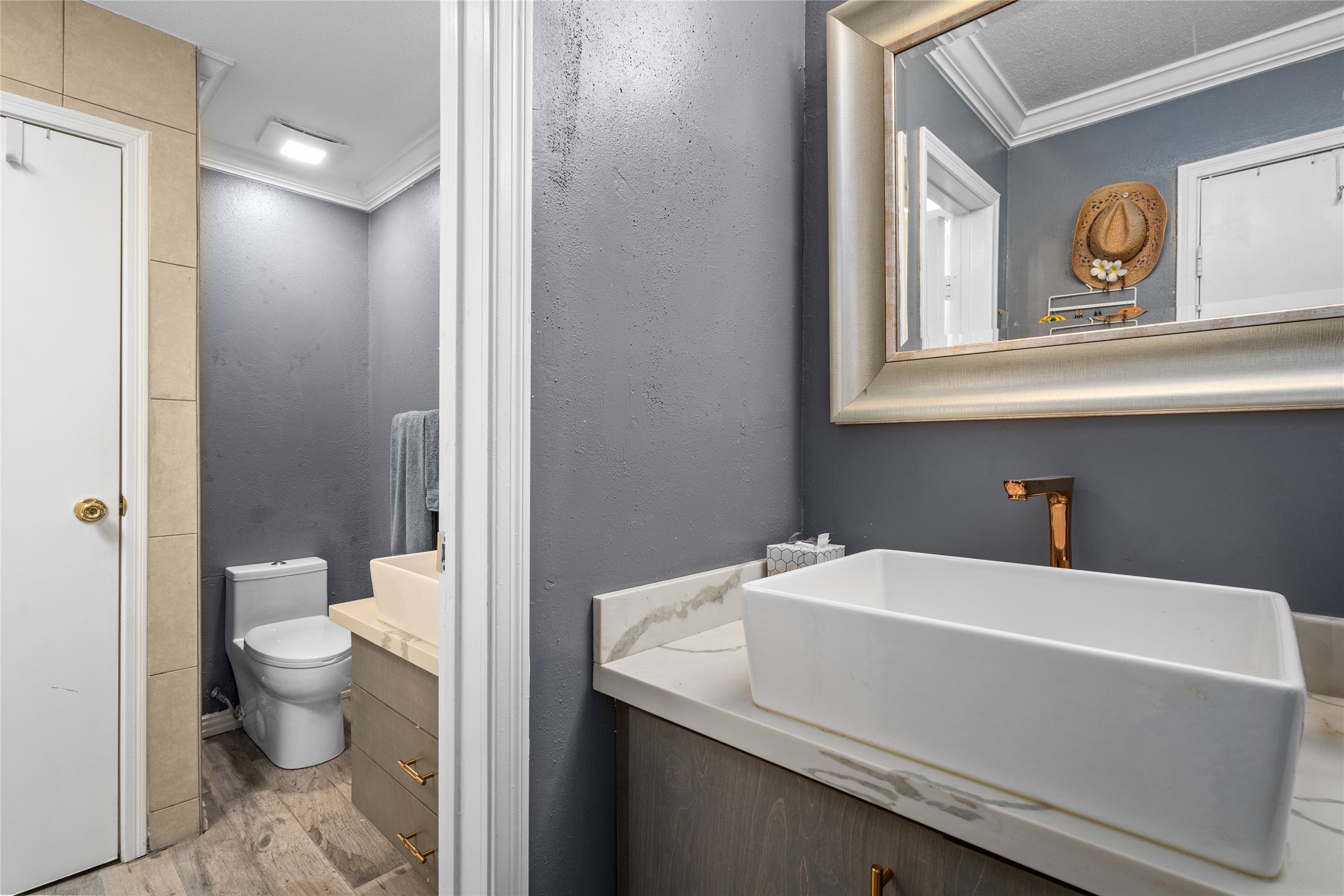 This stylish secondary bathroom features a contemporary vanity with a sleek countertop and a modern vessel sink. The two-part layout provides added functionality, separating the vanity area from the toilet and shower space. A neutral color scheme and elegant finishes enhance the overall aesthetic, creating a refined and inviting atmosphere.