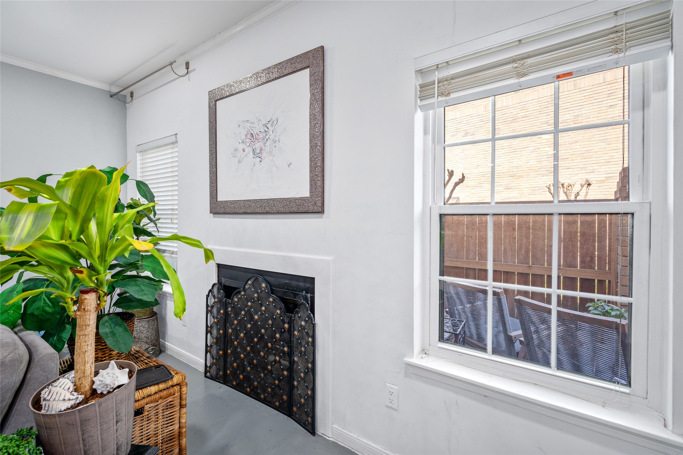 This inviting corner of the townhome features a charming fireplace framed by a decorative screen, adding warmth and character to the space. A large window allows for plenty of natural light and offers a view of the private patio, creating a bright and airy atmosphere. The neutral tones and clean design make this the perfect spot to relax and unwind.