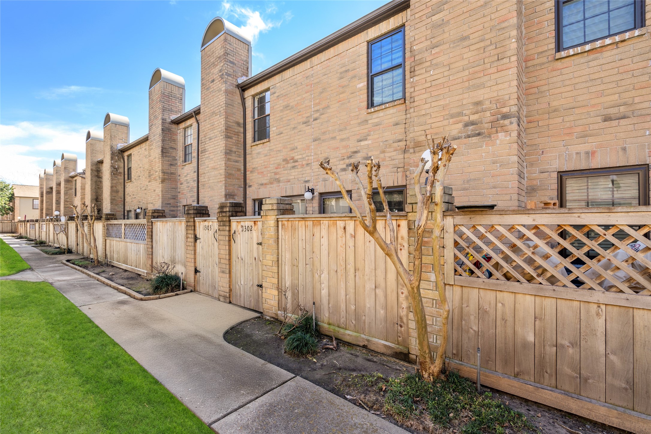Nestled in a well-maintained community, 9850 Pagewood Lane #1302 offers a charming townhome with a classic brick faade and a private gated entrance. A beautifully landscaped walkway leads to the front patio, providing a peaceful retreat. The striking row of chimneys adds architectural character, while the wooden fence ensures privacy. Enjoy the blend of convenience and charm in this inviting space.