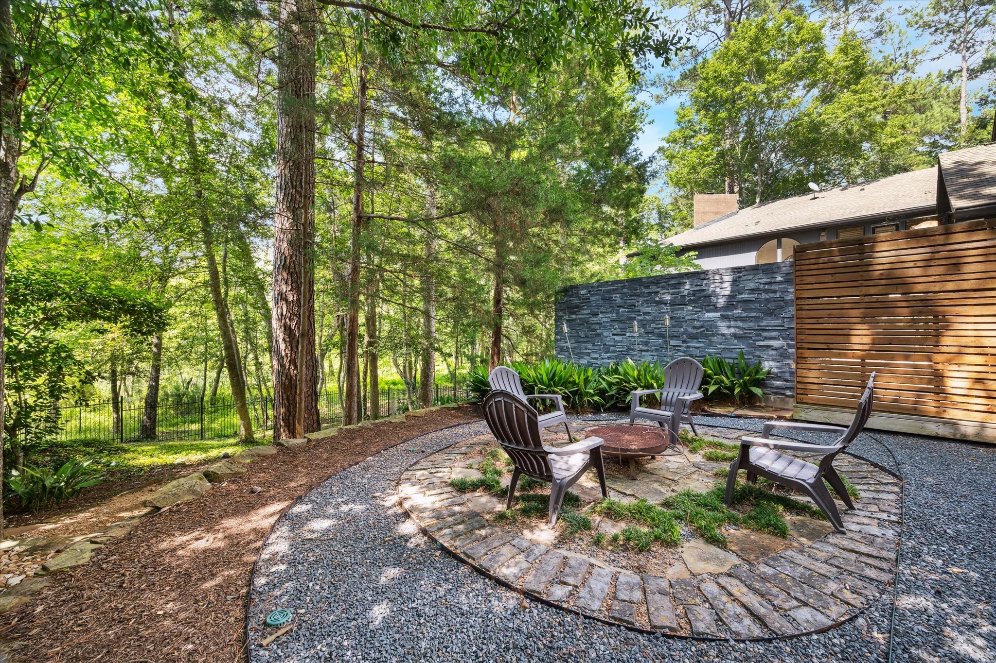 Cozy outdoor fire pit area nestled among mature trees, offering a serene, private retreat perfect for relaxing evenings or entertaining guests in a natural, wooded setting.