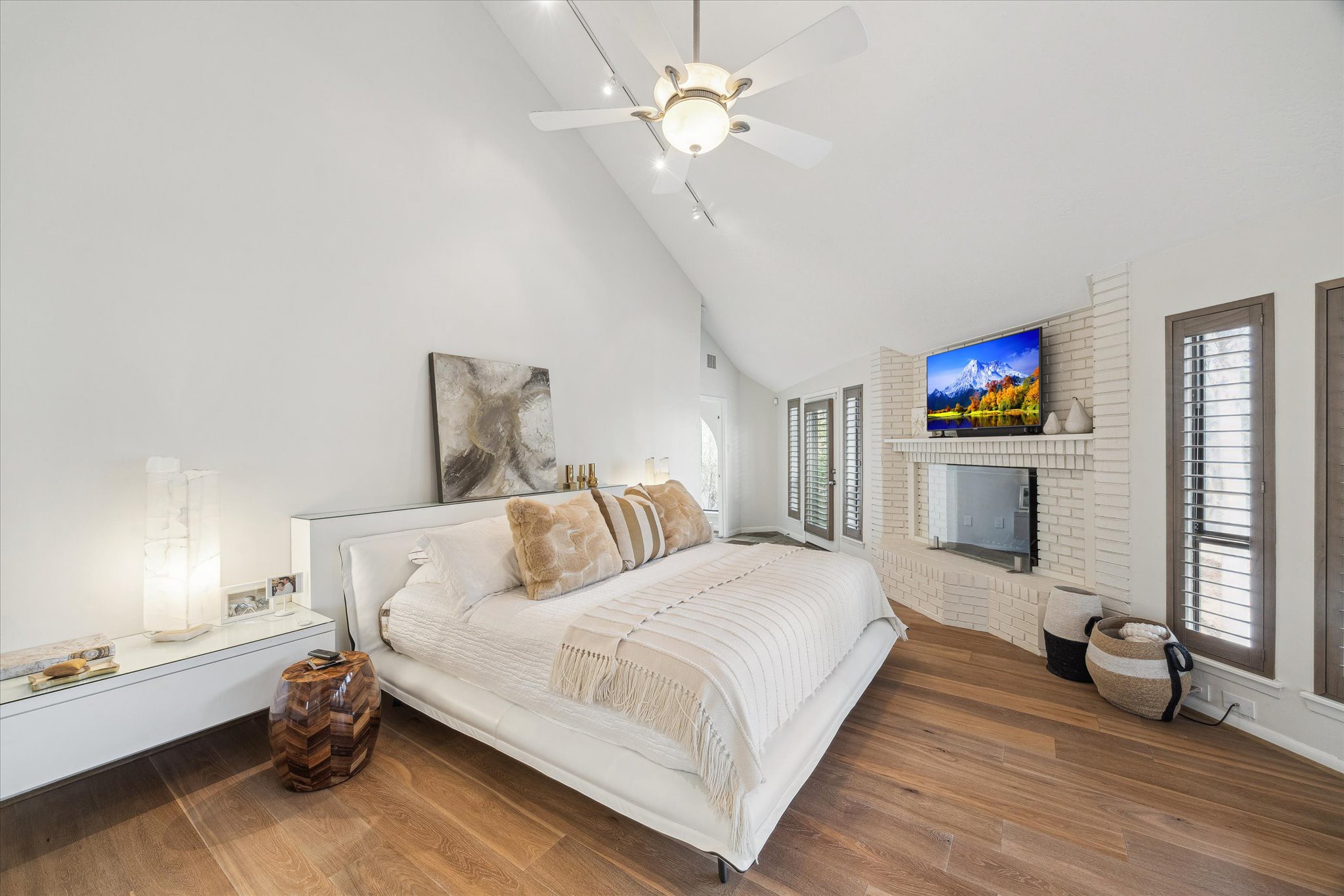 The raised primary suite offers a tranquil and elegant retreat, defined by vaulted ceilings and a private brick hearth that create an intimate sense of comfort and refinement.