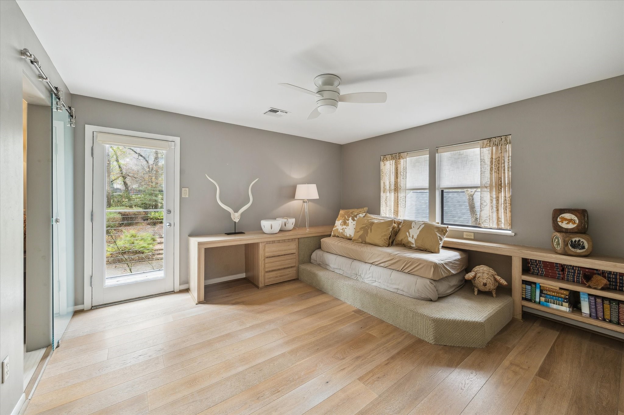 A thoughtfully designed secondary bedroom with an original built-in bed and balcony access, providing both cozy comfort and elevated views of the propertys lush surroundings.