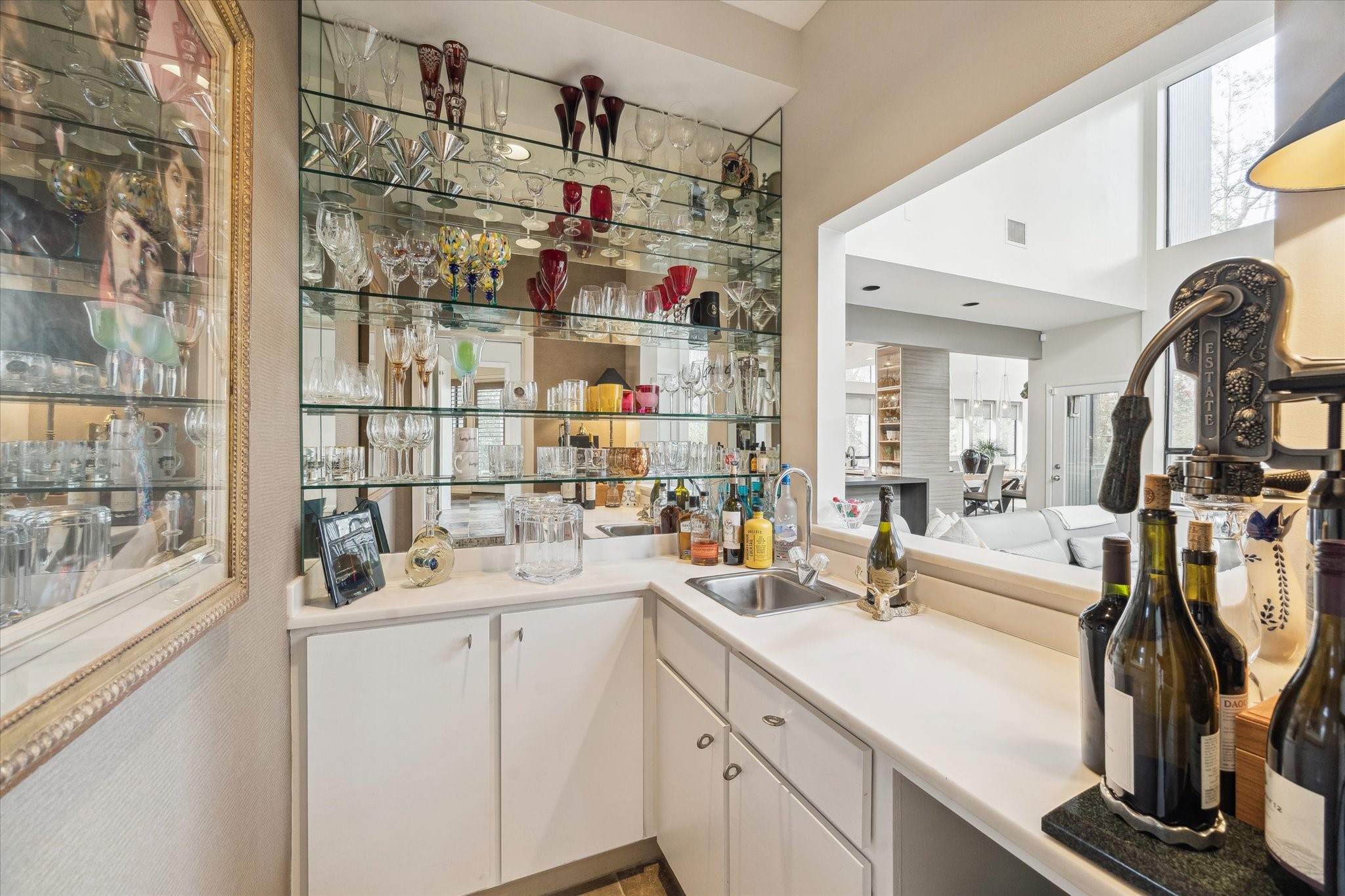 Sophisticated wet bar highlighted by a full mirrored wall and glass shelving, creating a dramatic focal point. Custom lower cabinetry provides generous storage, blending form and function for effortless entertaining and elevated gatherings.