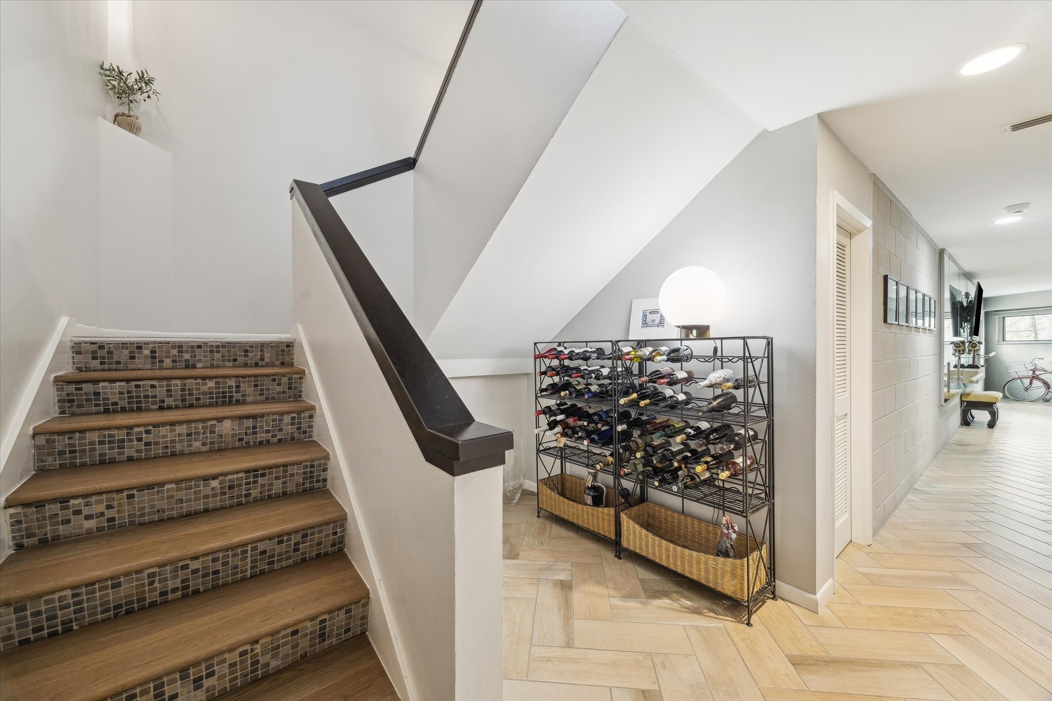 An architectural transition that feels as intentional as the rooms it connects. This is the lower level of the home which also offers a half bath, a flex space and an oversized utility room.