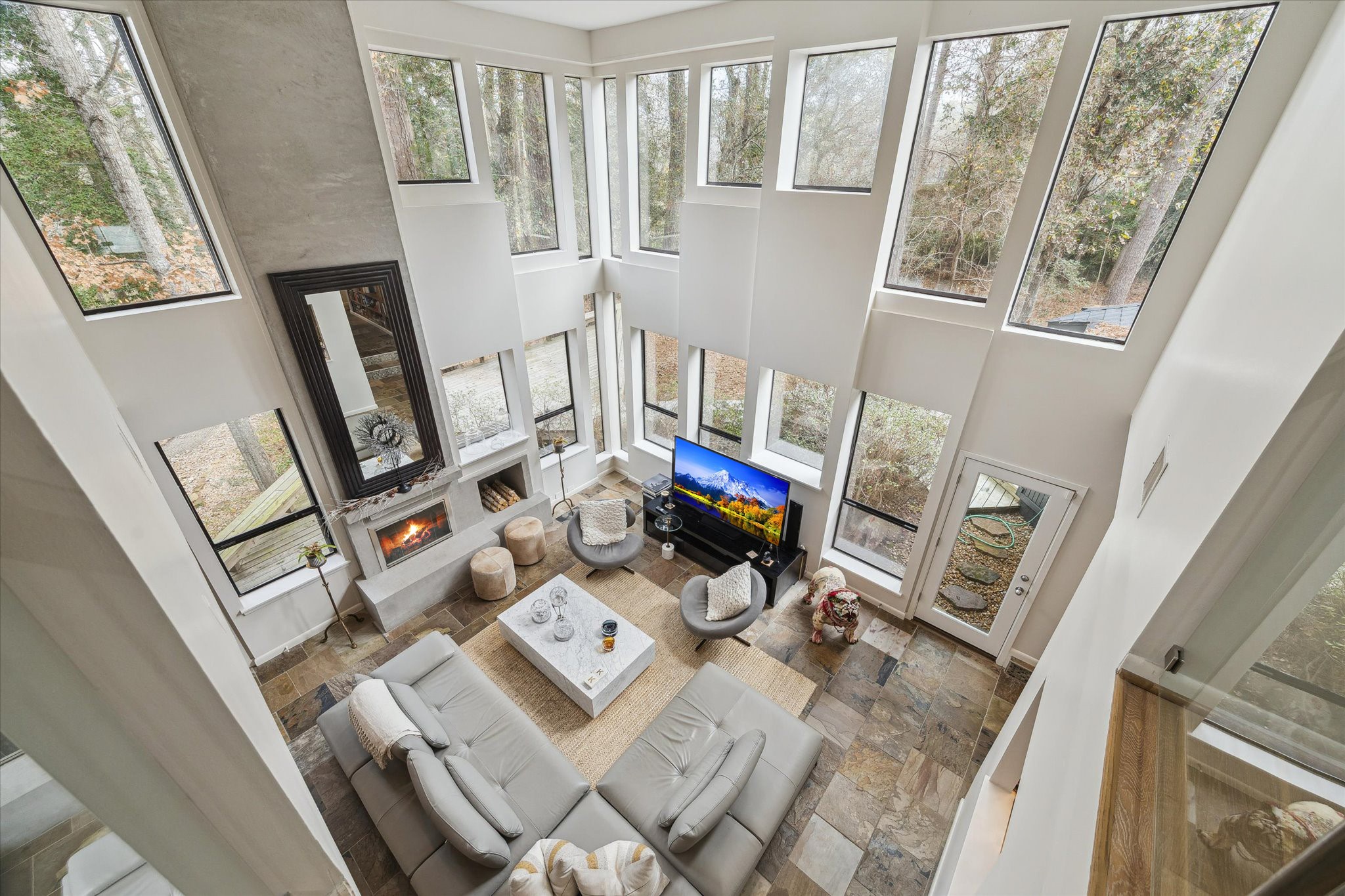 The loft office provides a unique perspective of the living room below, combining openness, natural light, and the tranquil feeling of treetop living.