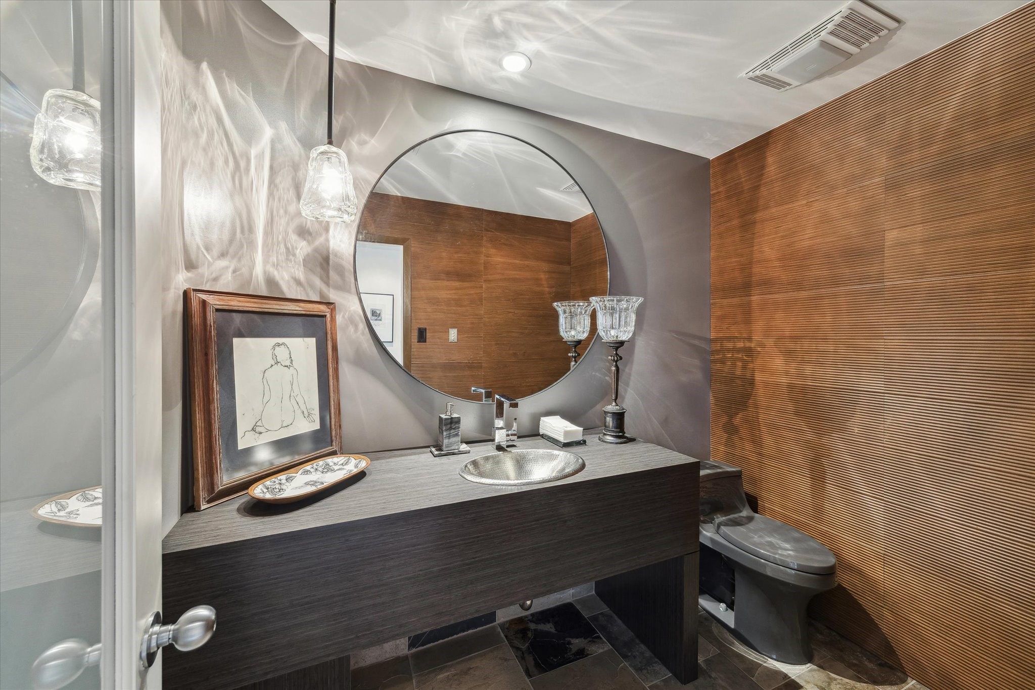 A stylish powder room that reflects the homes attention to detail featuring warm wood accents that tie seamlessly into the surrounding natural landscape. The vanity mirror is excluded.