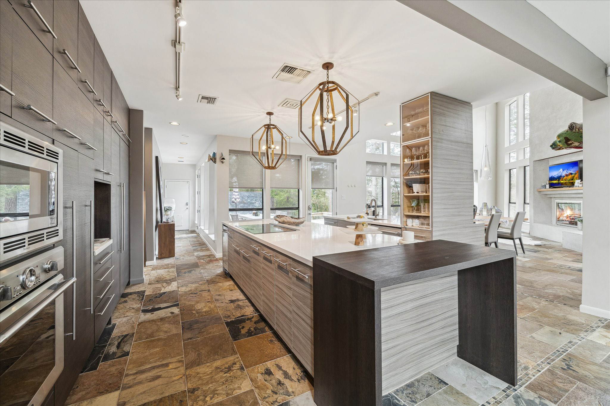 A large center island provides ample workspace and storage, ideal for entertaining and everyday use. Designer pendant lighting and track lighting add architectural interest, while floor-to-ceiling cabinetry offers abundant storage.