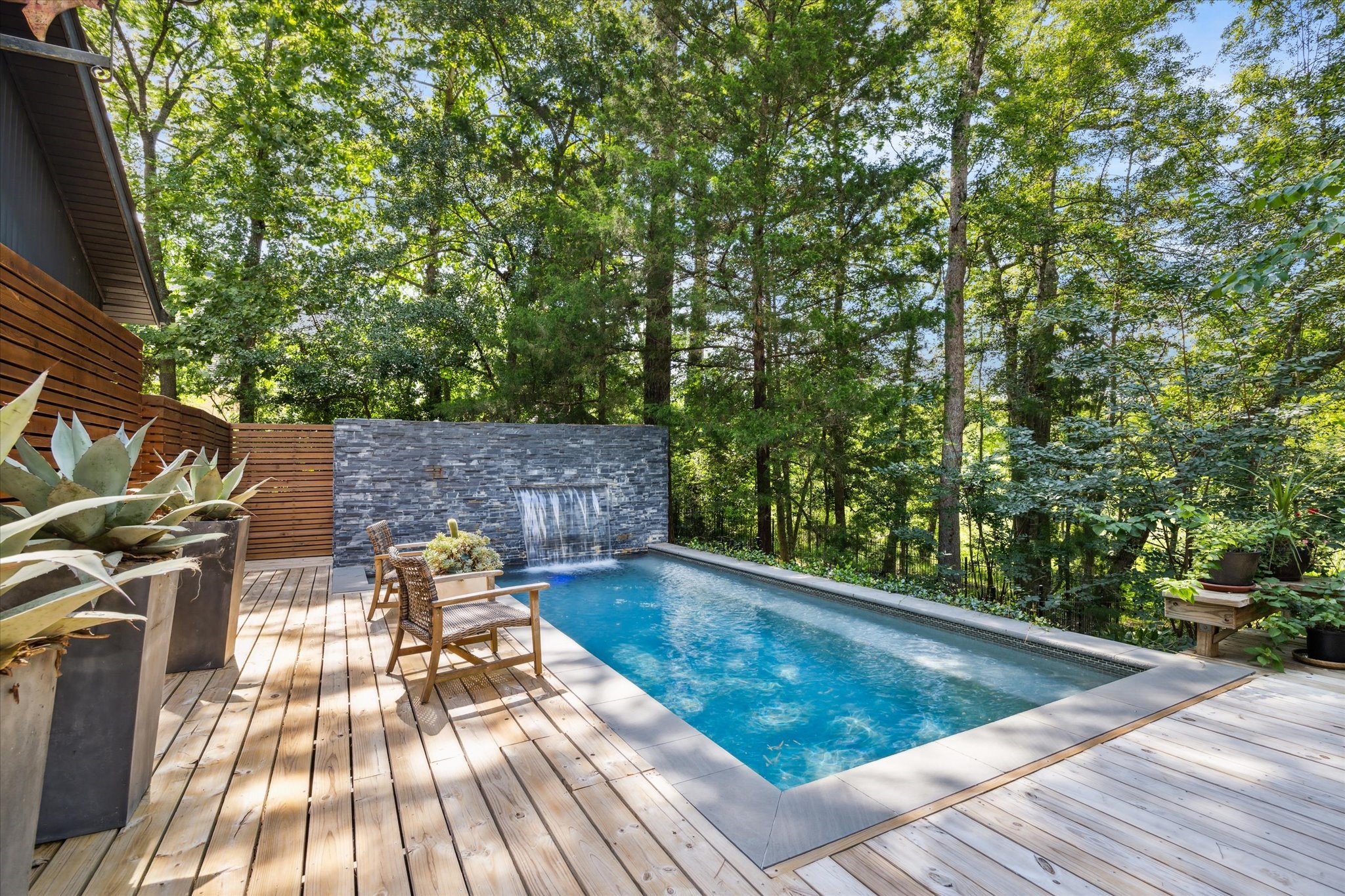 The swimming pool with a stone wall water feature and a sprawling wooden deck invites you and your guests to relax under the sun or moonlight.