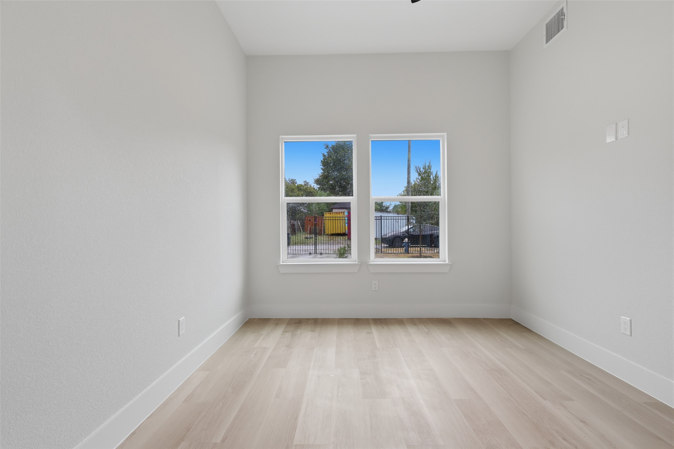 Bright and inviting bedroom room with large windows, sleek light LVP flooring, and neutral walls, offering a versatile space filled with natural light.